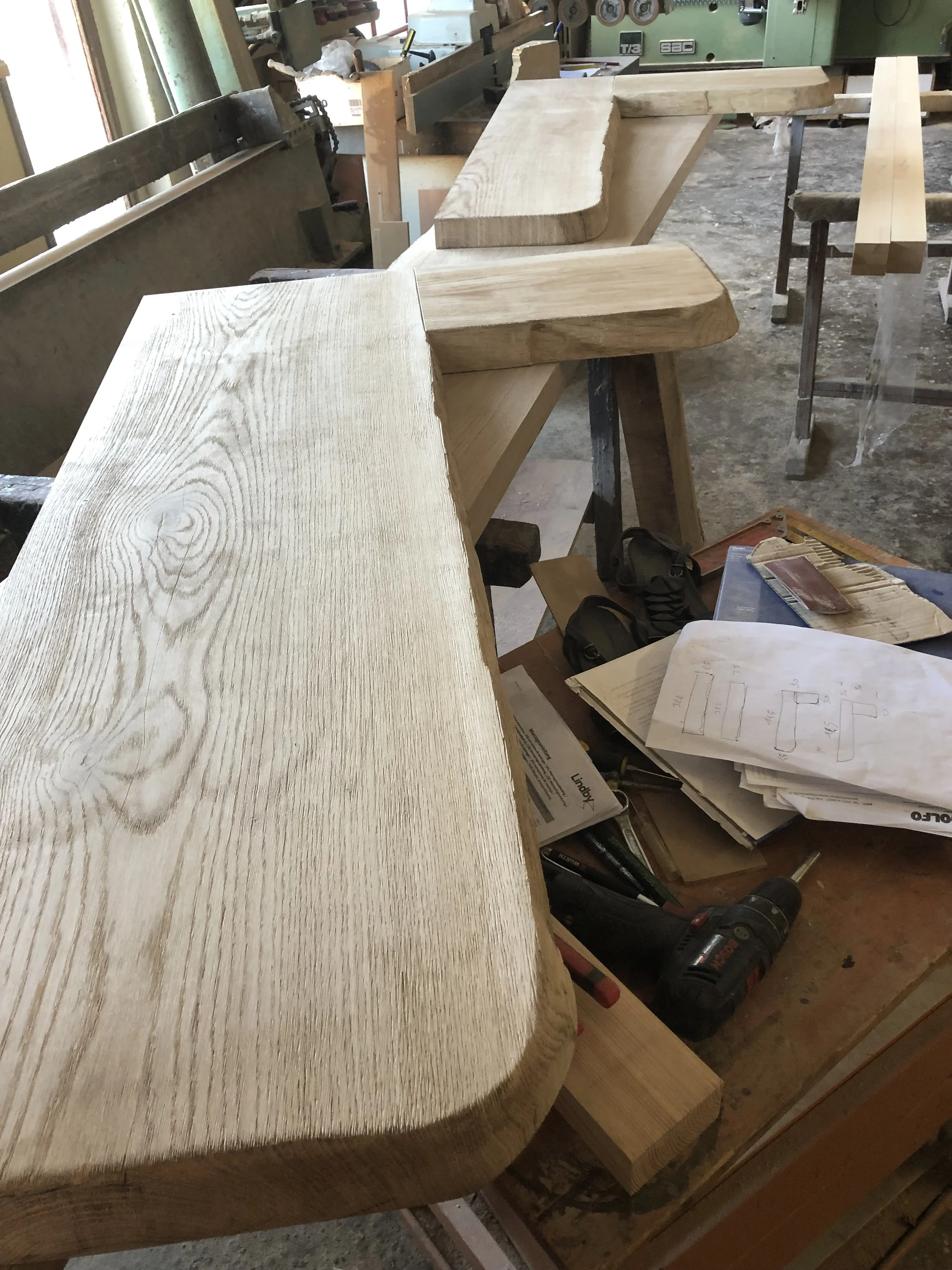 Lavoro in corso su un banco di falegnameria con assi di legno e strumenti di lavoro.