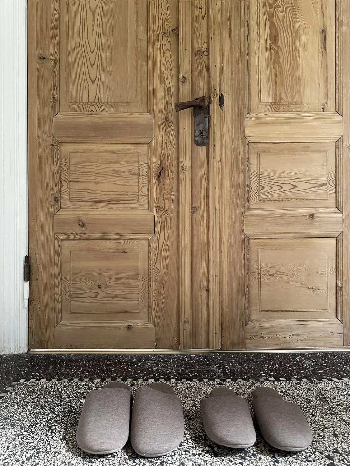 Hausschuhe für Gäste vor Holztüre im Eingangsbereich des Ferienhauses