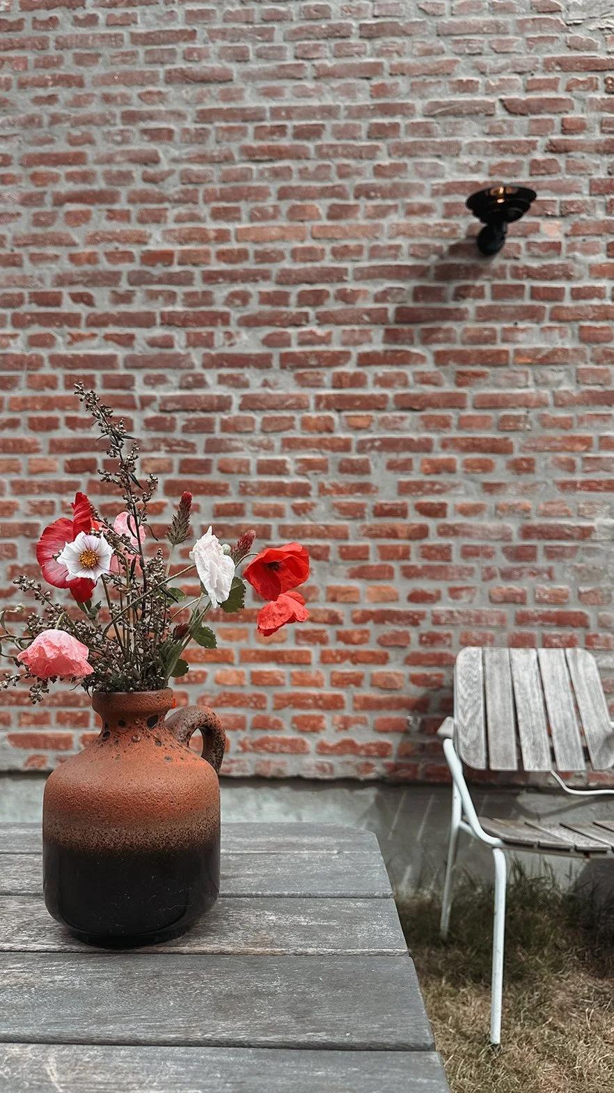 Sitzplatz im Garten vor der Backstein-Fassade des Schusterhauses