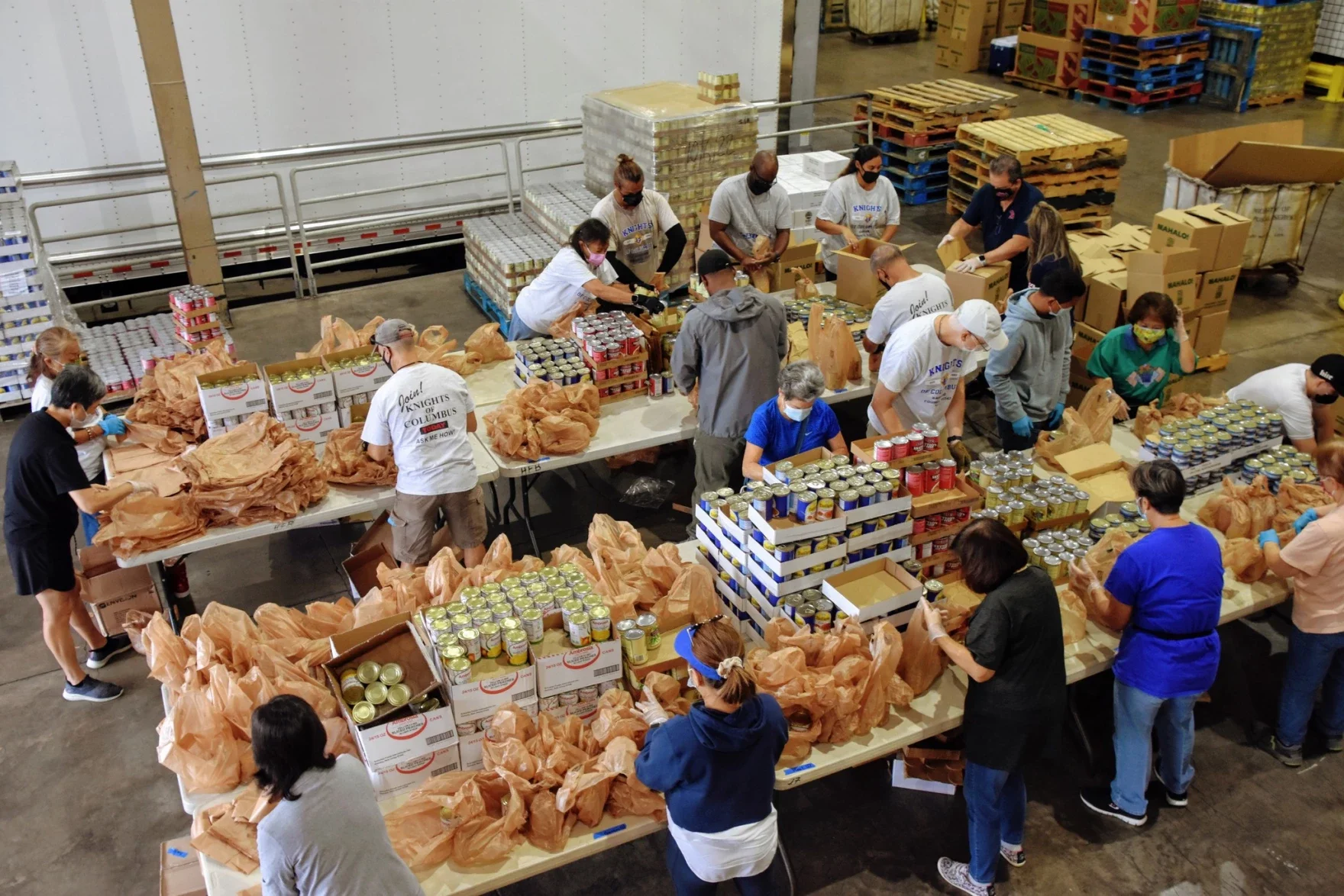 People working together in a warehouse packing canned goods and supplies for distribution.