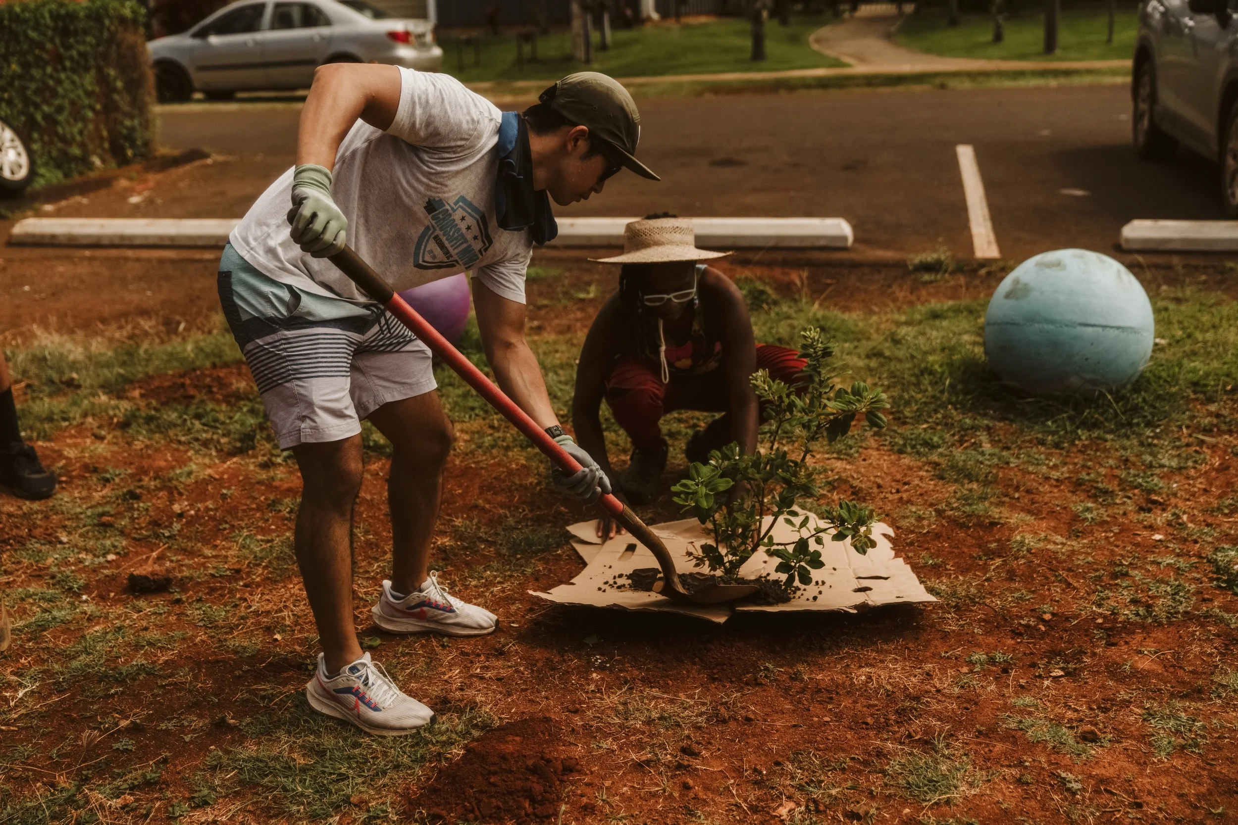 A large group of people sitting at a long dining table, eating pizza during a social gathering or event, with colorful walls and ambient lighting.