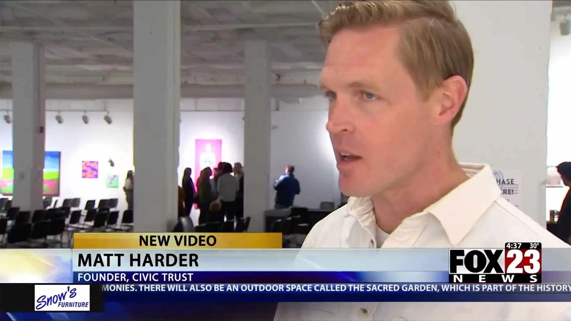 Interview with Matt Harder, founder of Civic Trust, at an art gallery or exhibition space with colorful artwork on the walls and people viewing the art in the background.