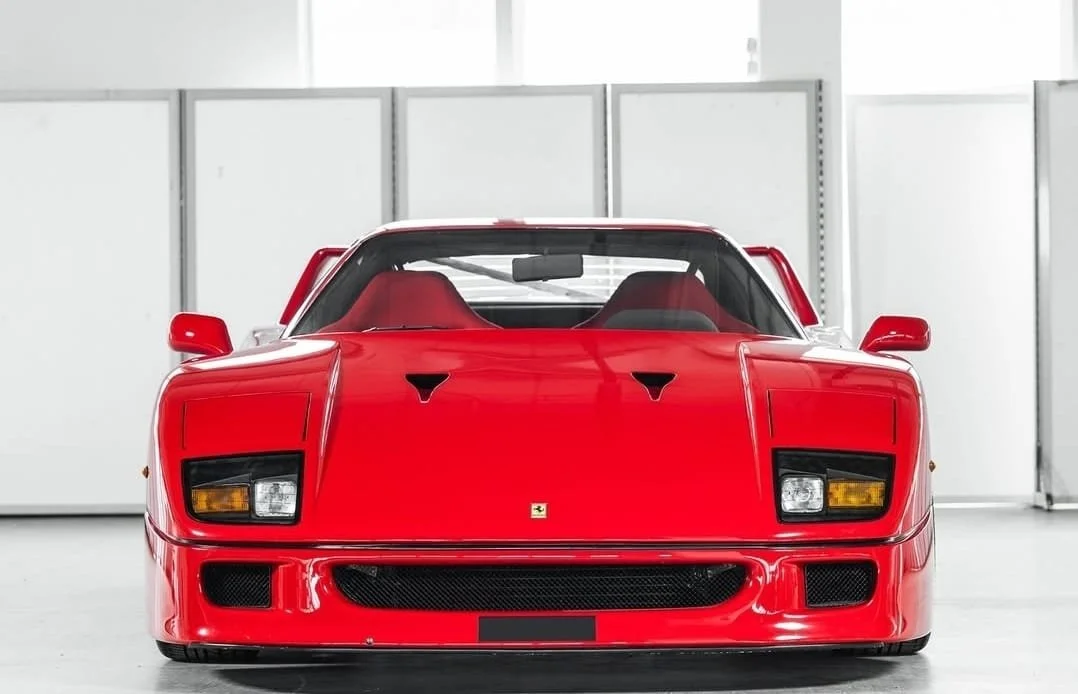 Front view of a sleek, iconic red sports car in a well-lit indoor setting.