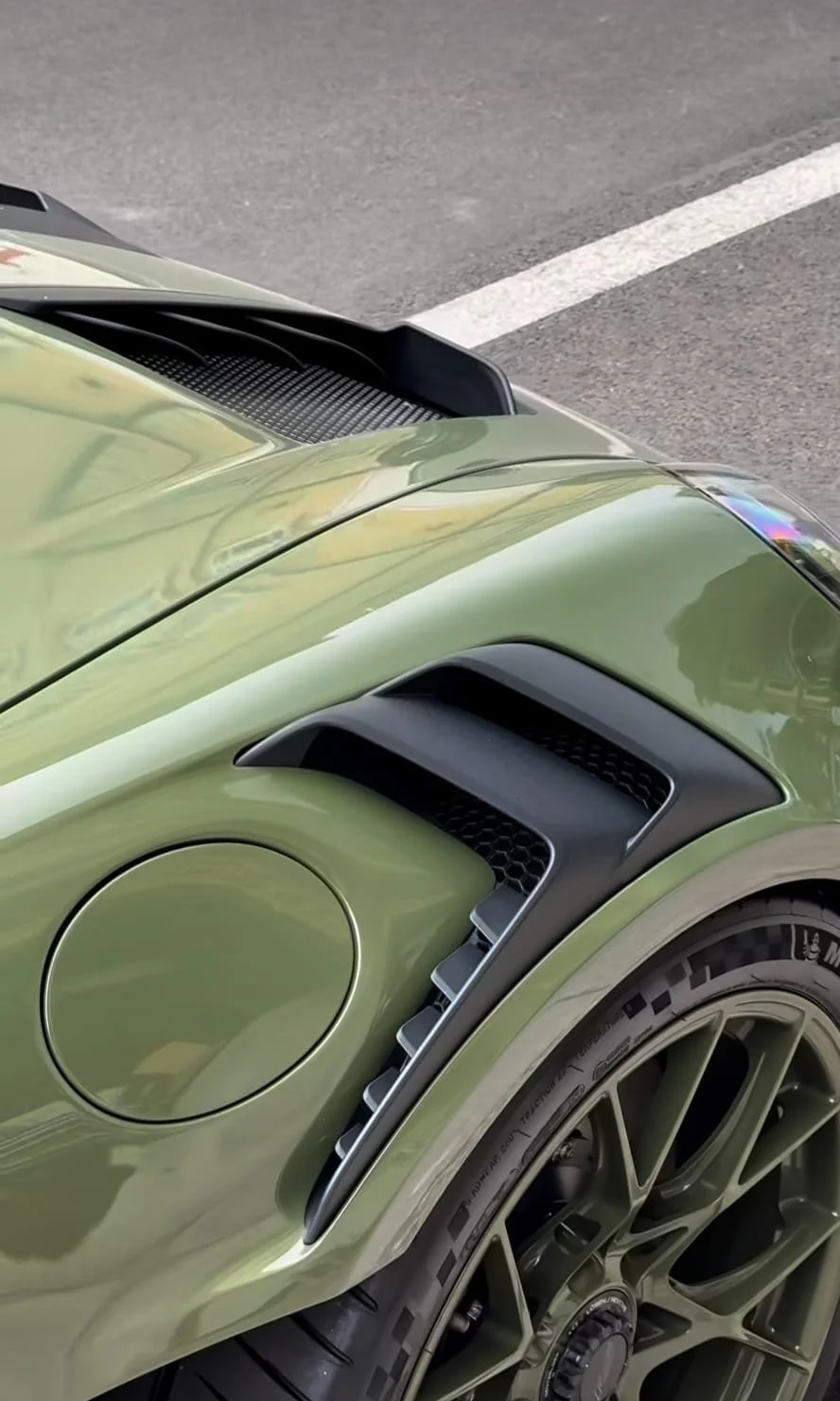 Close-up of a shiny green sports car's front left fender