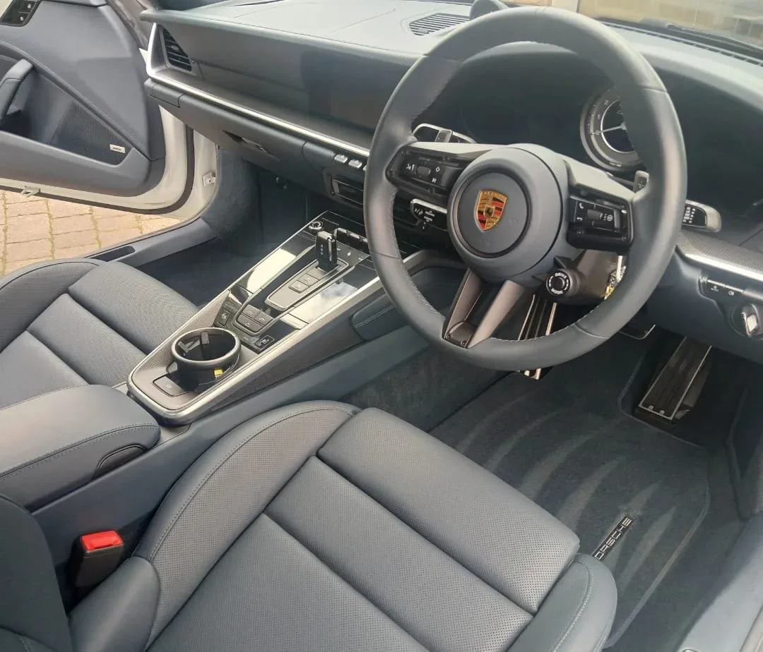 interior of a luxury car, featuring a sleek black steering wheel with a prominent logo, modern dashboard, and plush leather seats