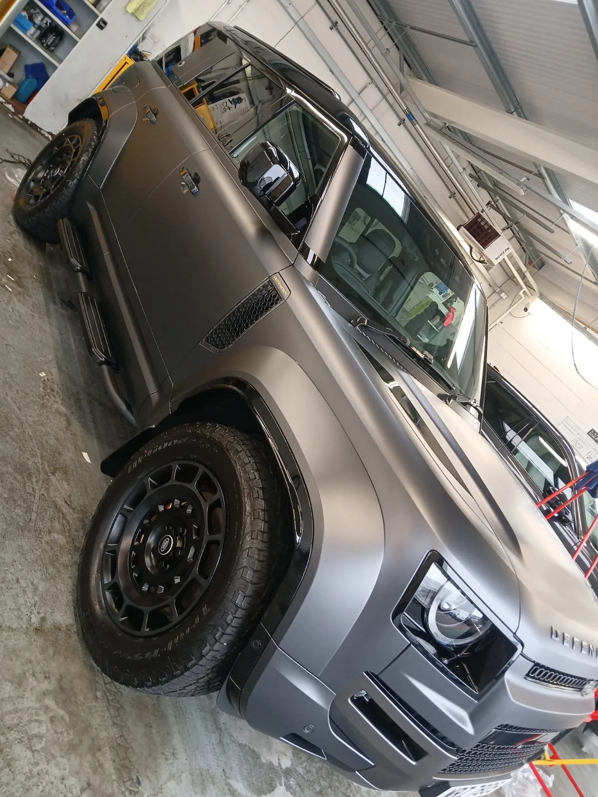 Sleek gray SUV with matte finish in a garage, showcasing modern design and large tires