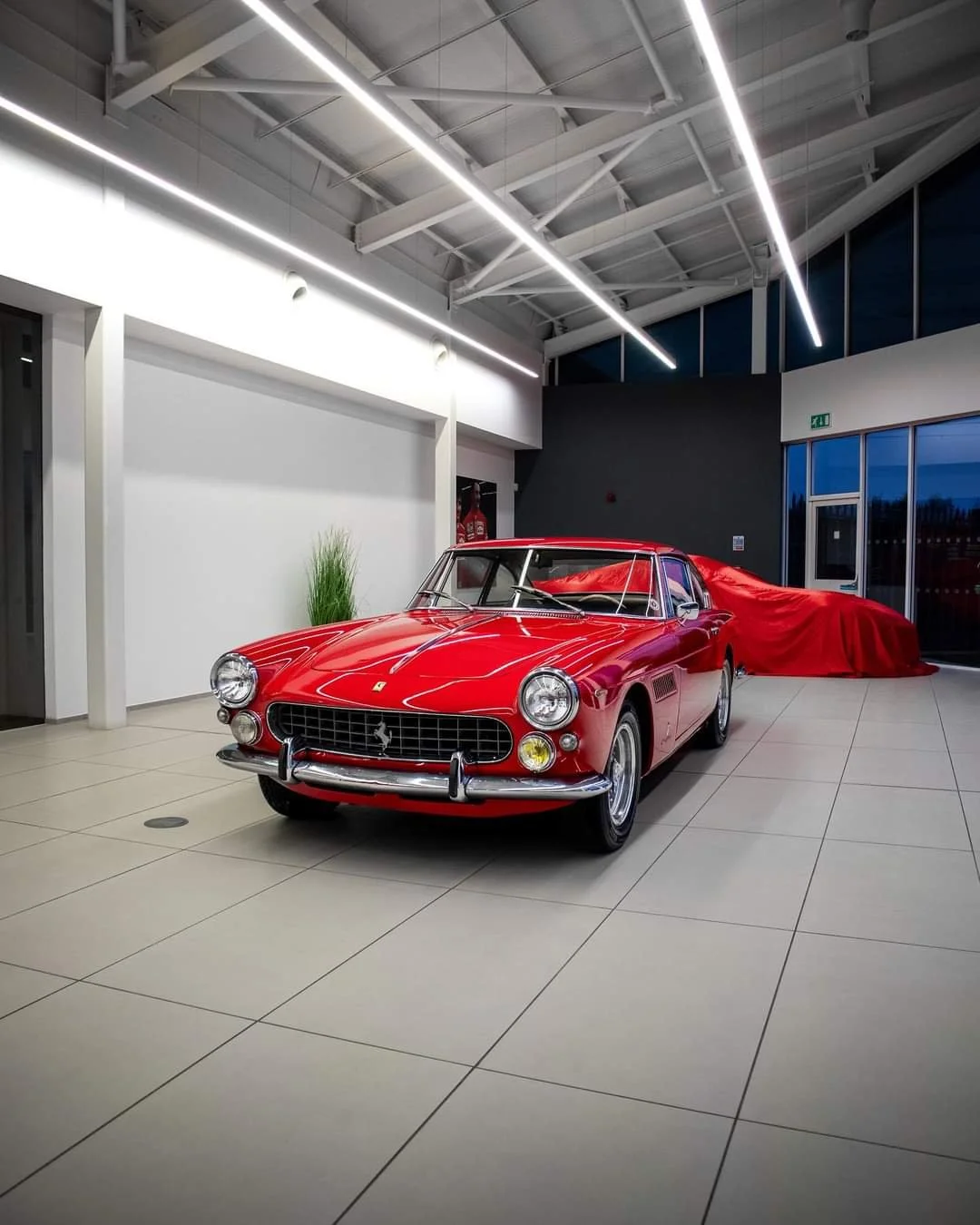 A classic red sports car with a sleek design and chrome details is parked in a clean garage