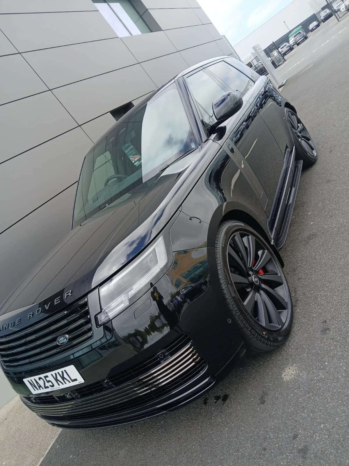 A sleek black Range Rover SUV is parked beside a modern building