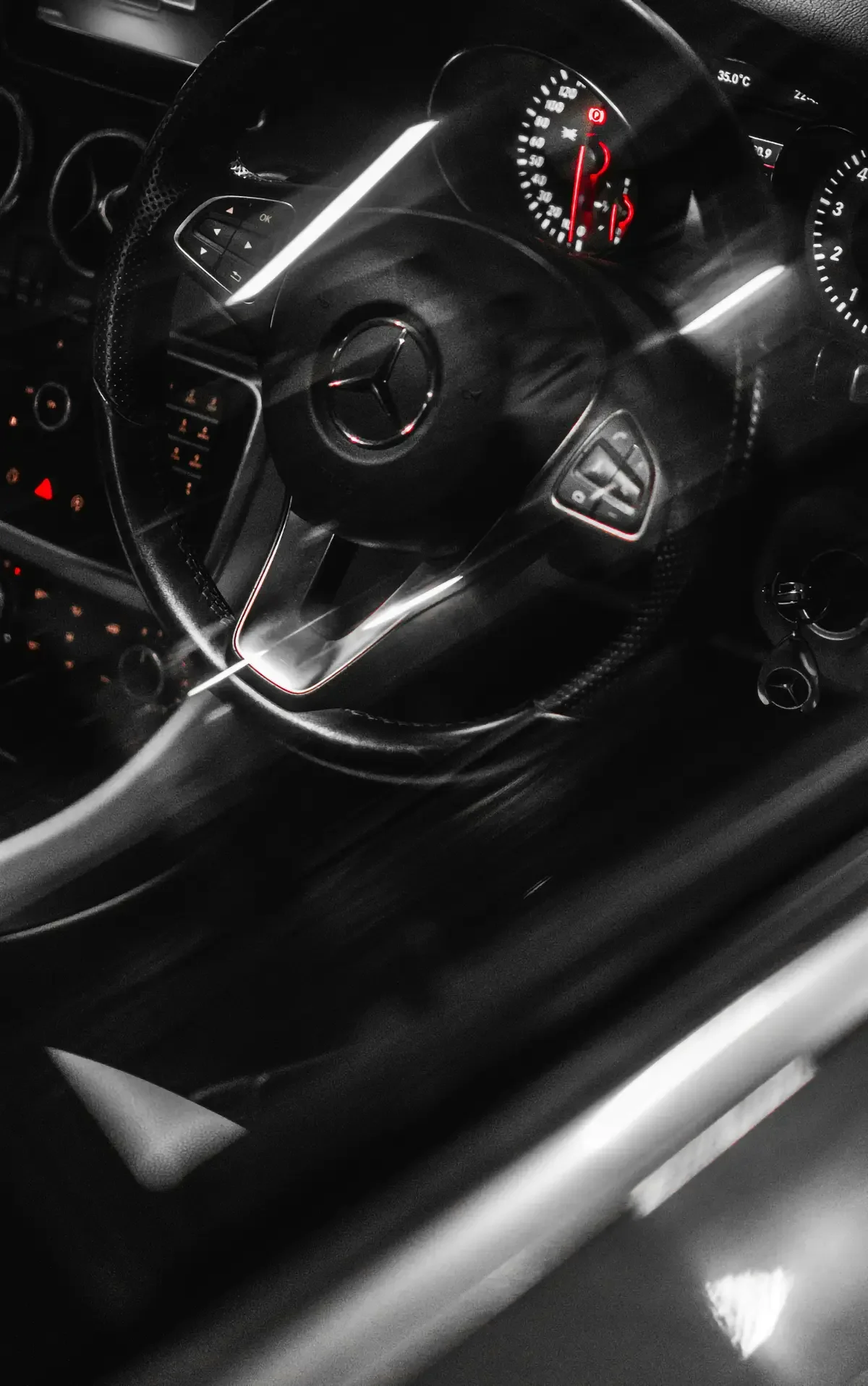 Close-up of a luxury car interior showing a steering wheel with a prominent logo, sleek dashboard with glowing dials, and modern aesthetic.