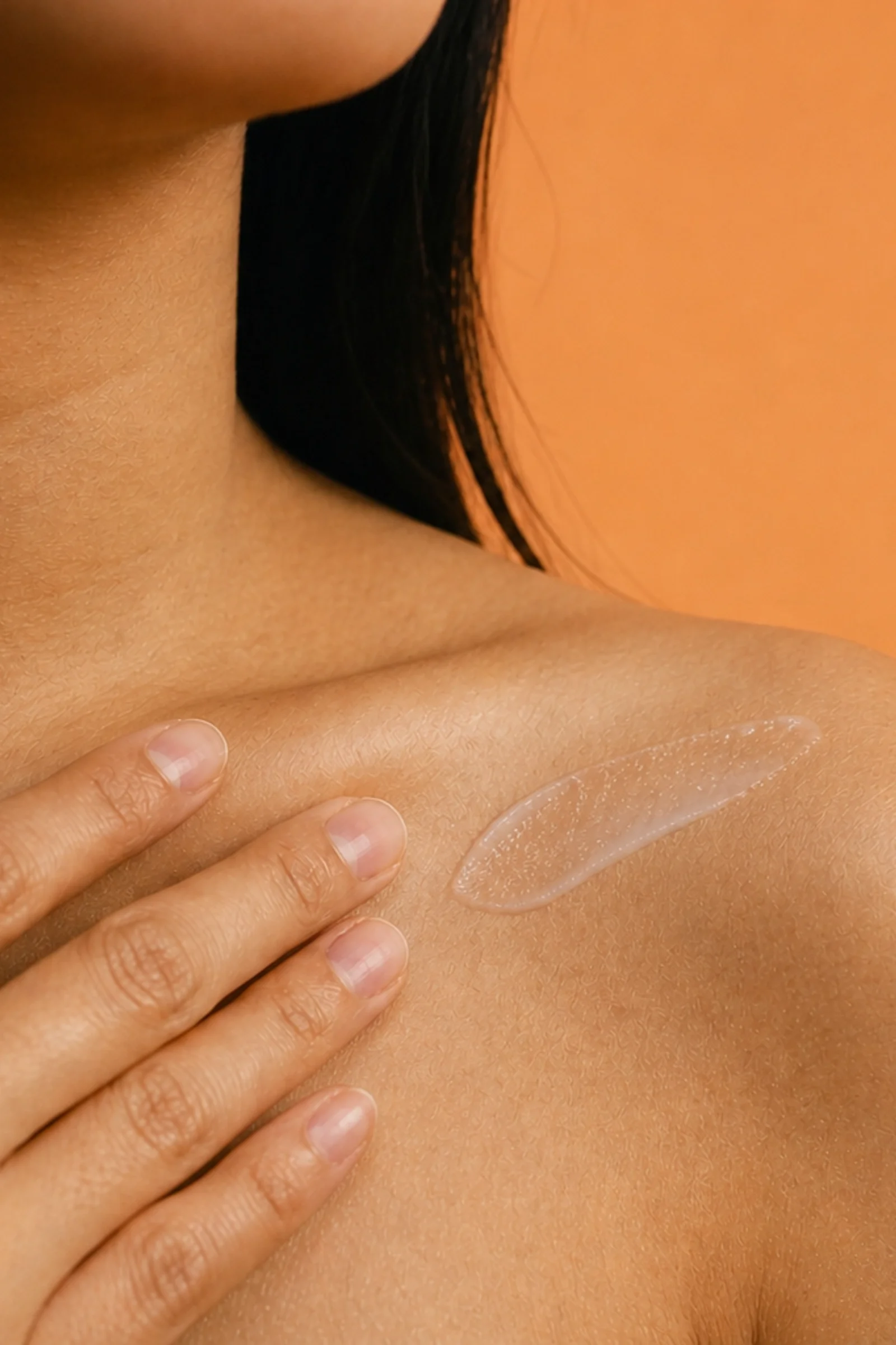 A close-up of a person with dark hair and fair skin, showing part of their face and neck, with fingers touching their shoulder and an SPF50+ cream layer, Aurtela by TWINE Medicals.