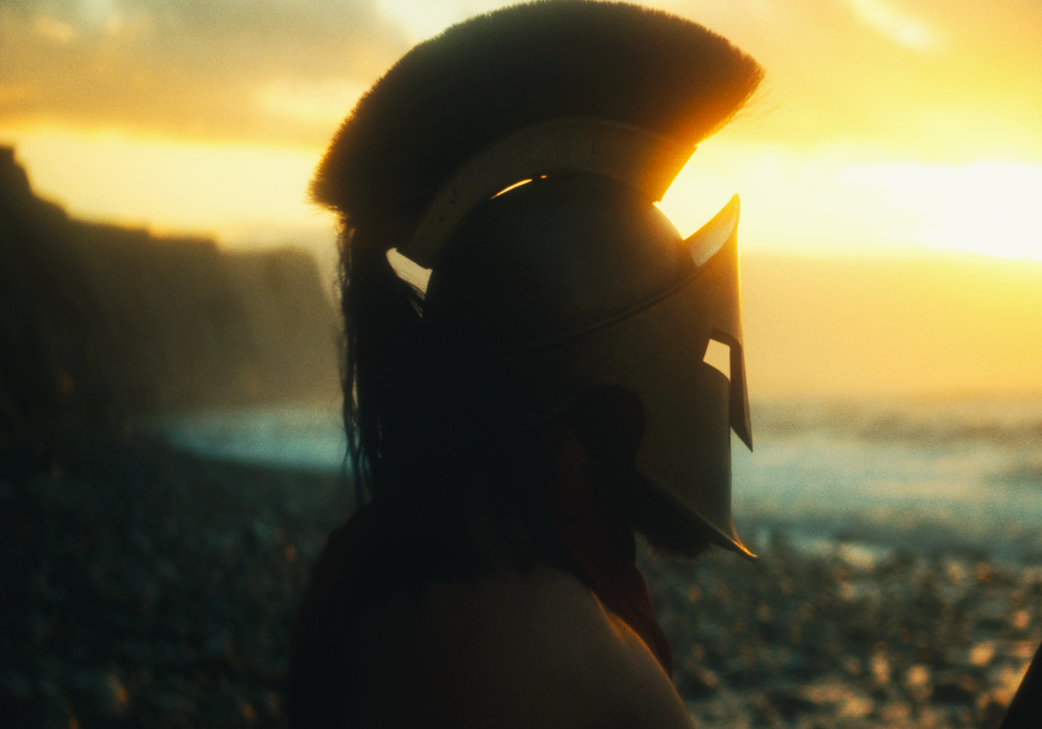 Silhouette of a person wearing a helmet by the beach during sunset.