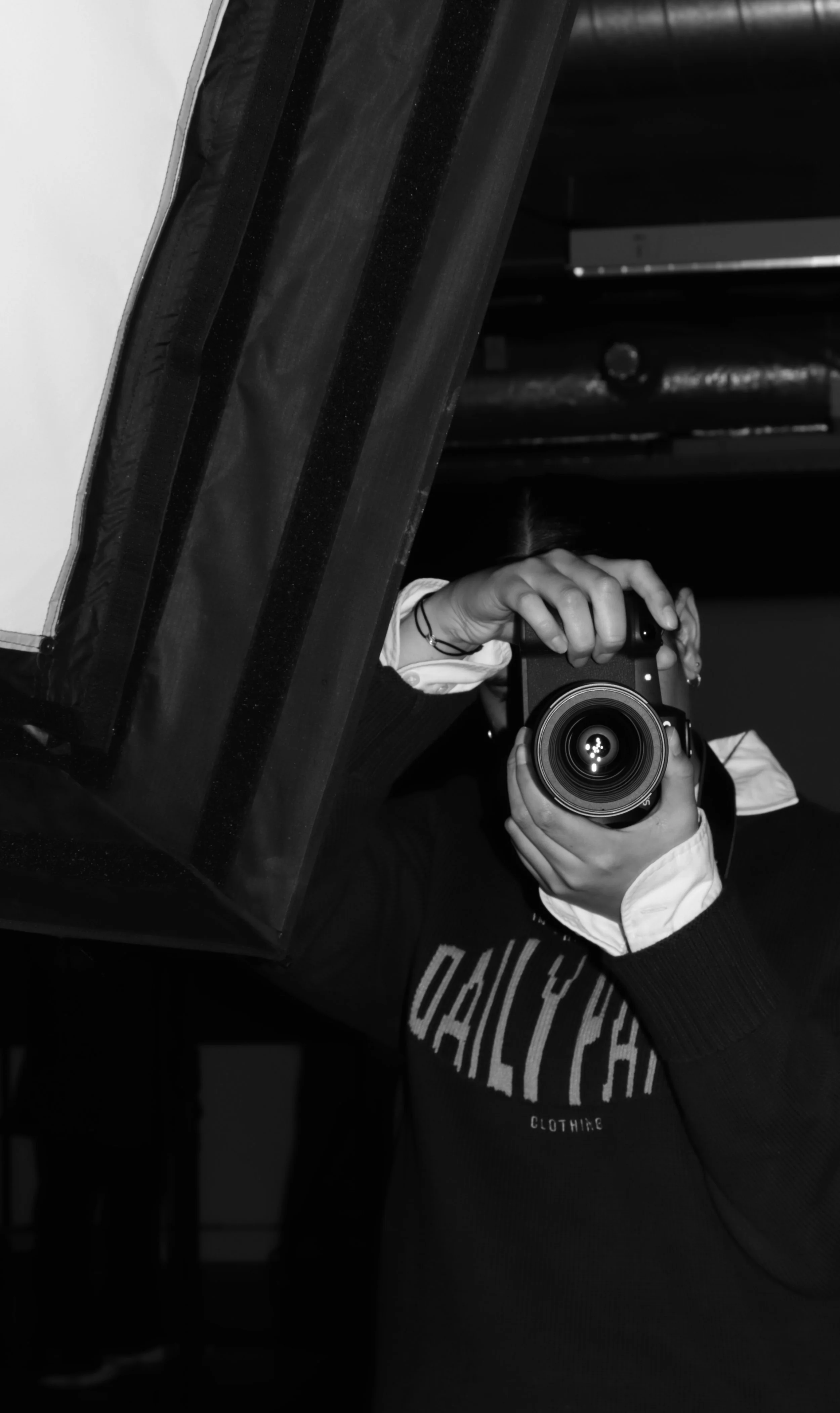 Persoon die in spiegel reflecteert met camera in hand, zwart-wit foto.