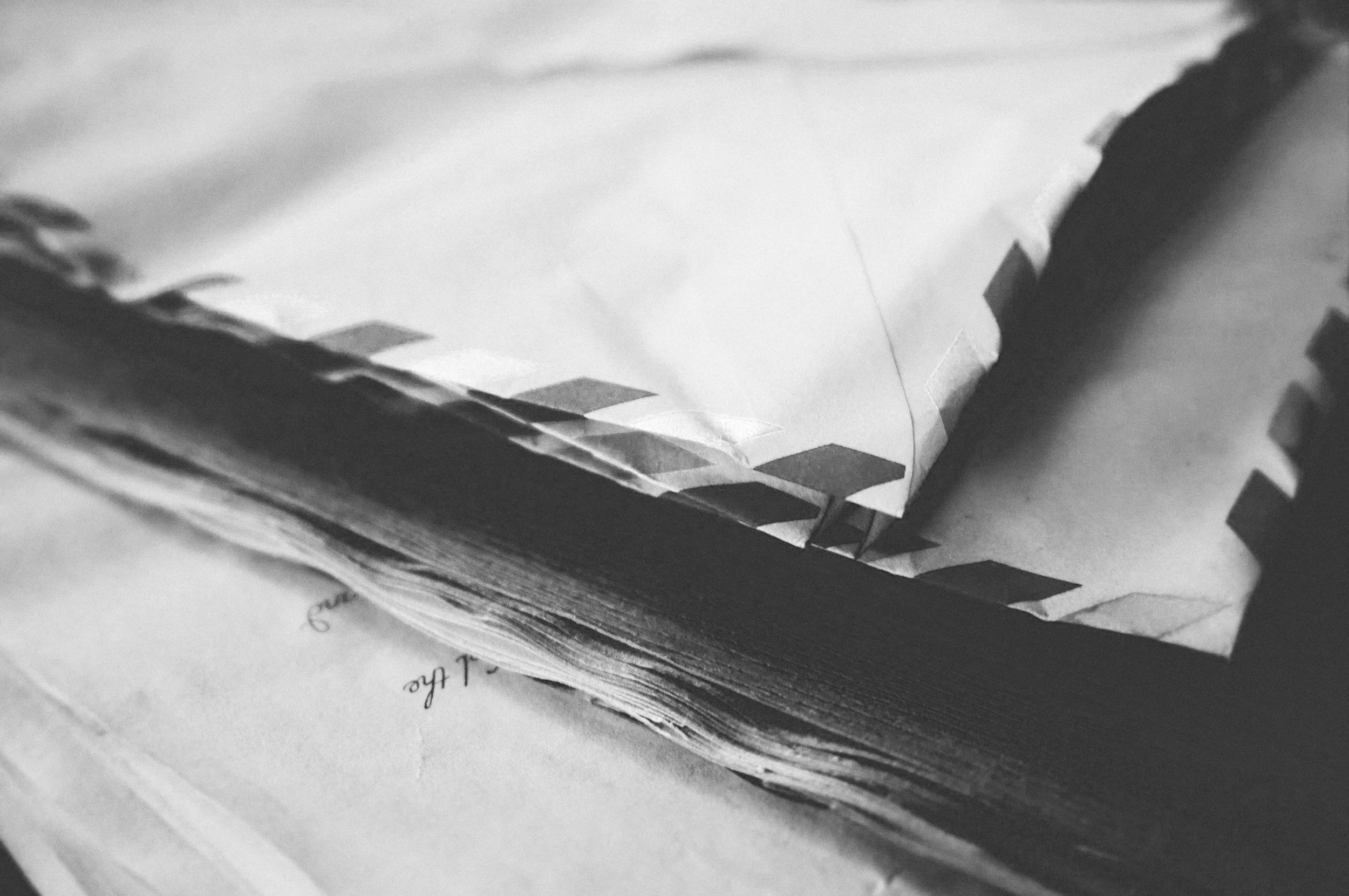 Papel y documentos apilados con una carpeta negra, en blanco y negro.