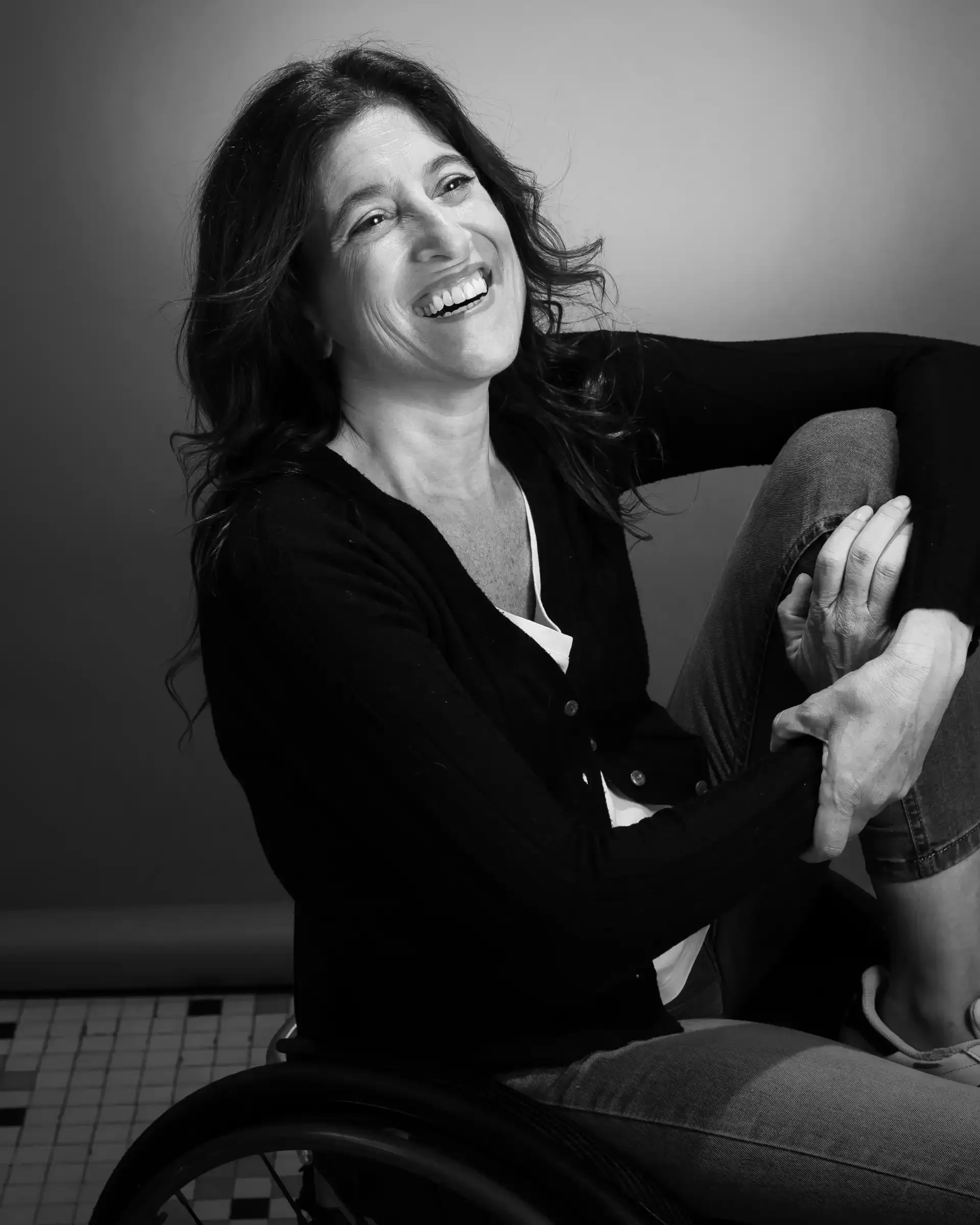 Mujer sonriente en silla de ruedas, en negro y blanco.