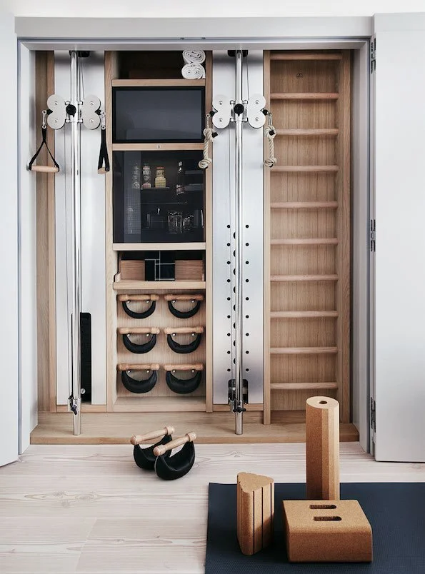 Organized home gym storage unit with resistance bands, kettlebells, foam blocks, and a black exercise mat.