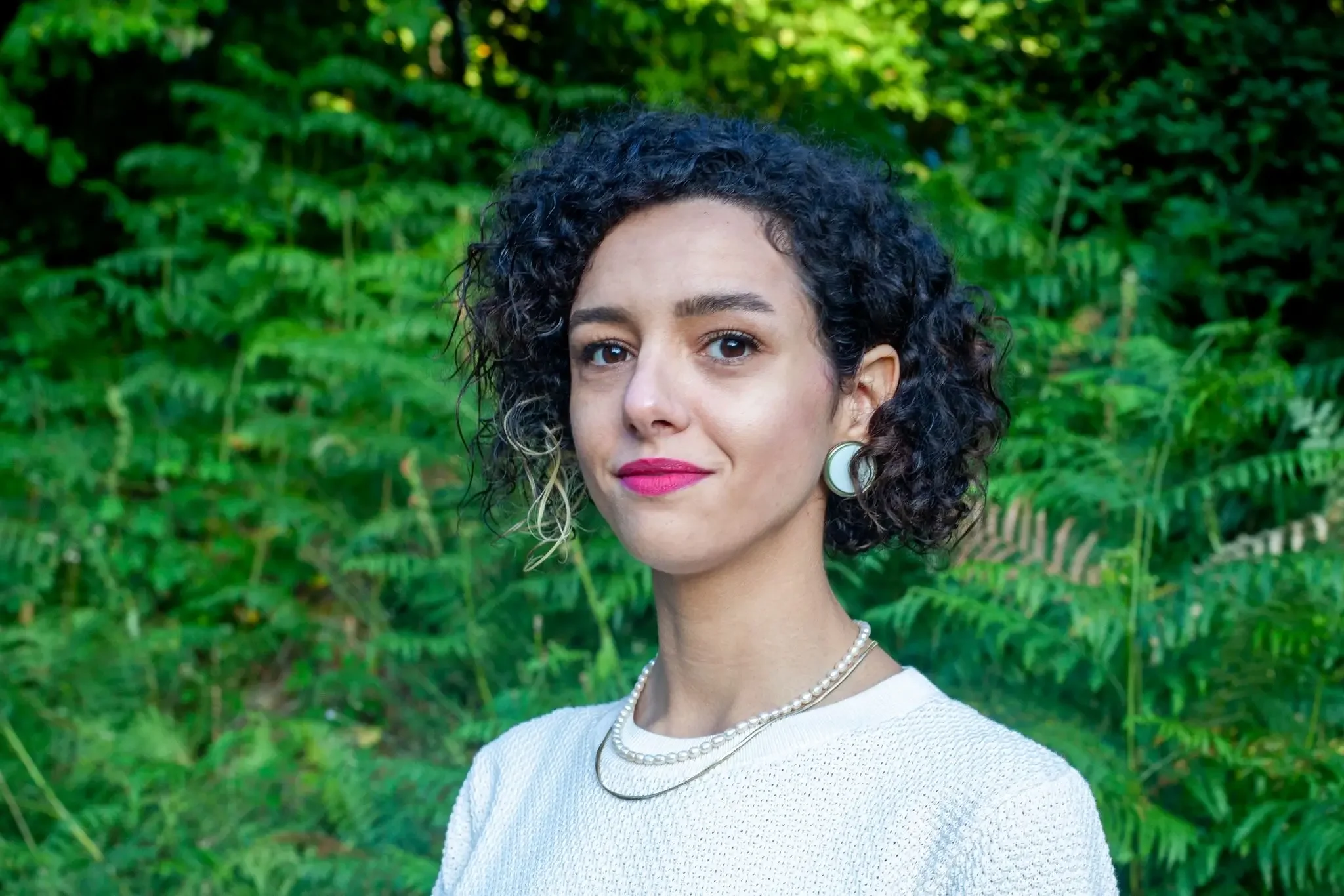 Dilan Yalnız, clinical psychologist in Paris, photographed in a natural green setting symbolizing calm and mental clarity.