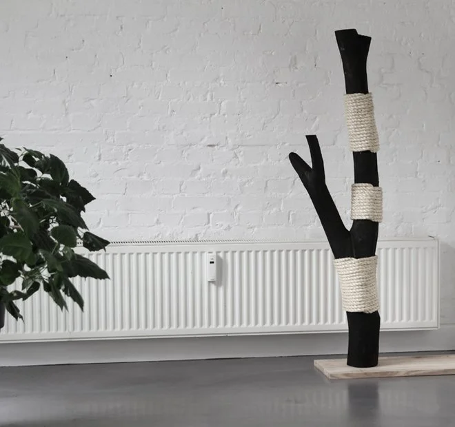 Designer cat scratching post in black wood and natural sisal placed in a modern living room