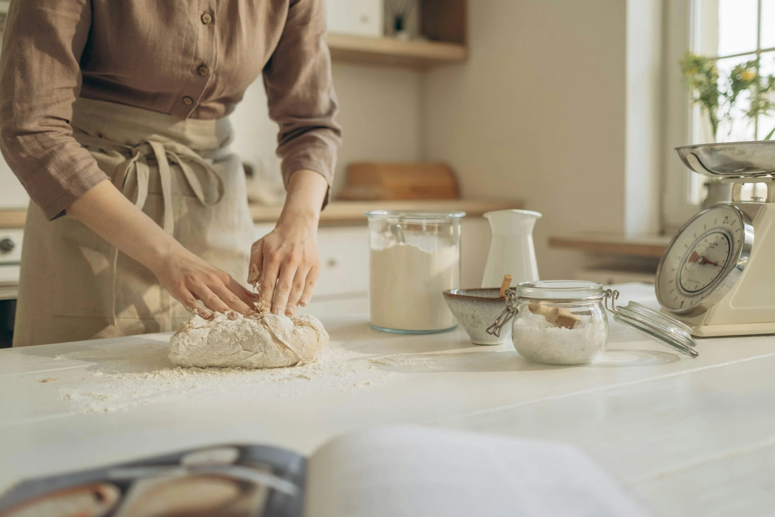Hands kneading homemade sourdough bread on a flour dusted surface, reflecting Elena Pop's passion for cooking and nourishing food