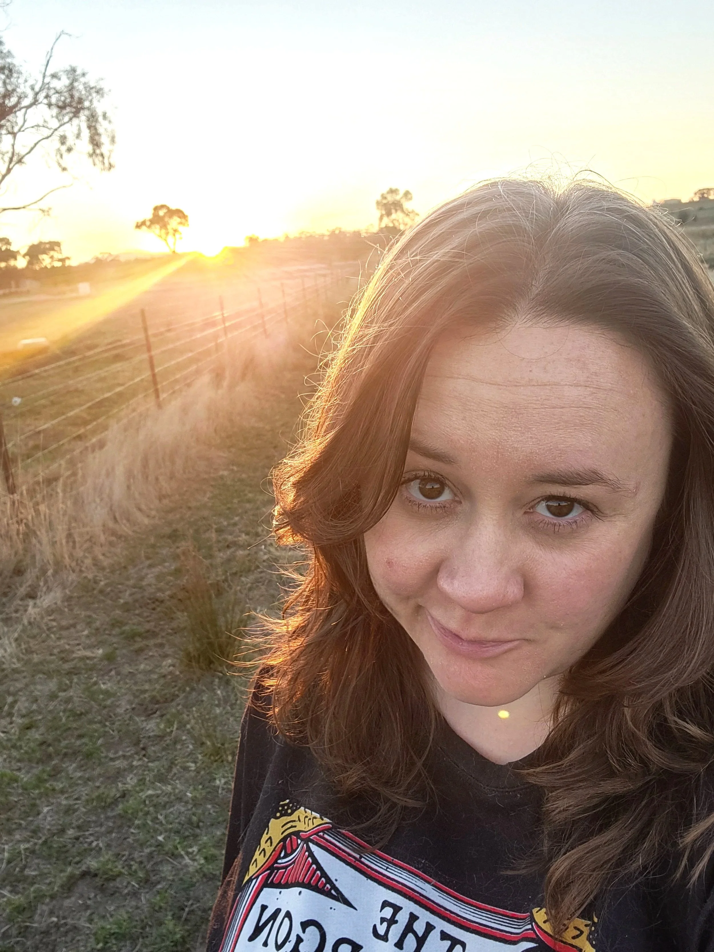 A picture of our founder, Samantha, standing on her family's farm at sunset.