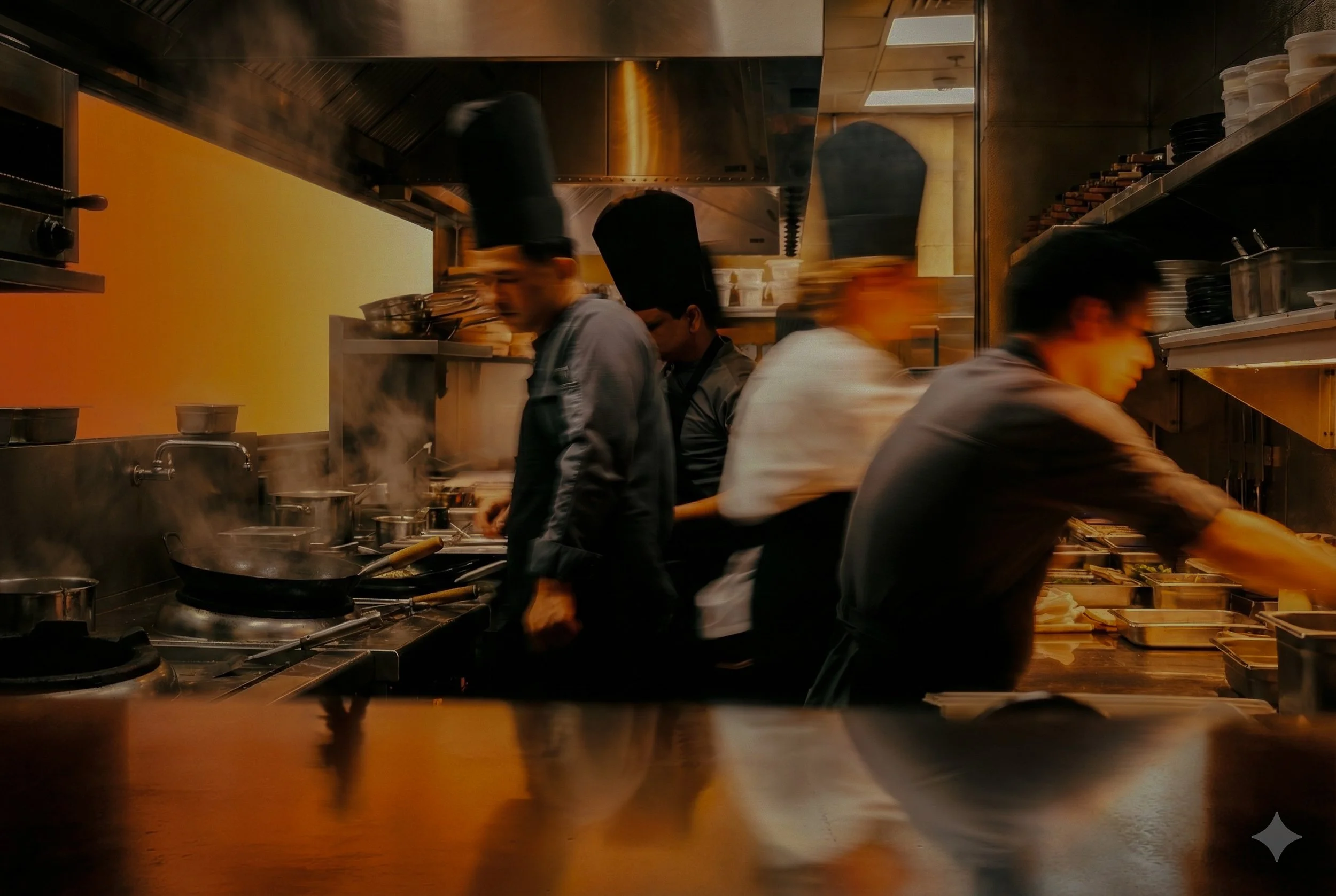 Four chefs working in a busy restaurant kitchen, preparing food at the stove