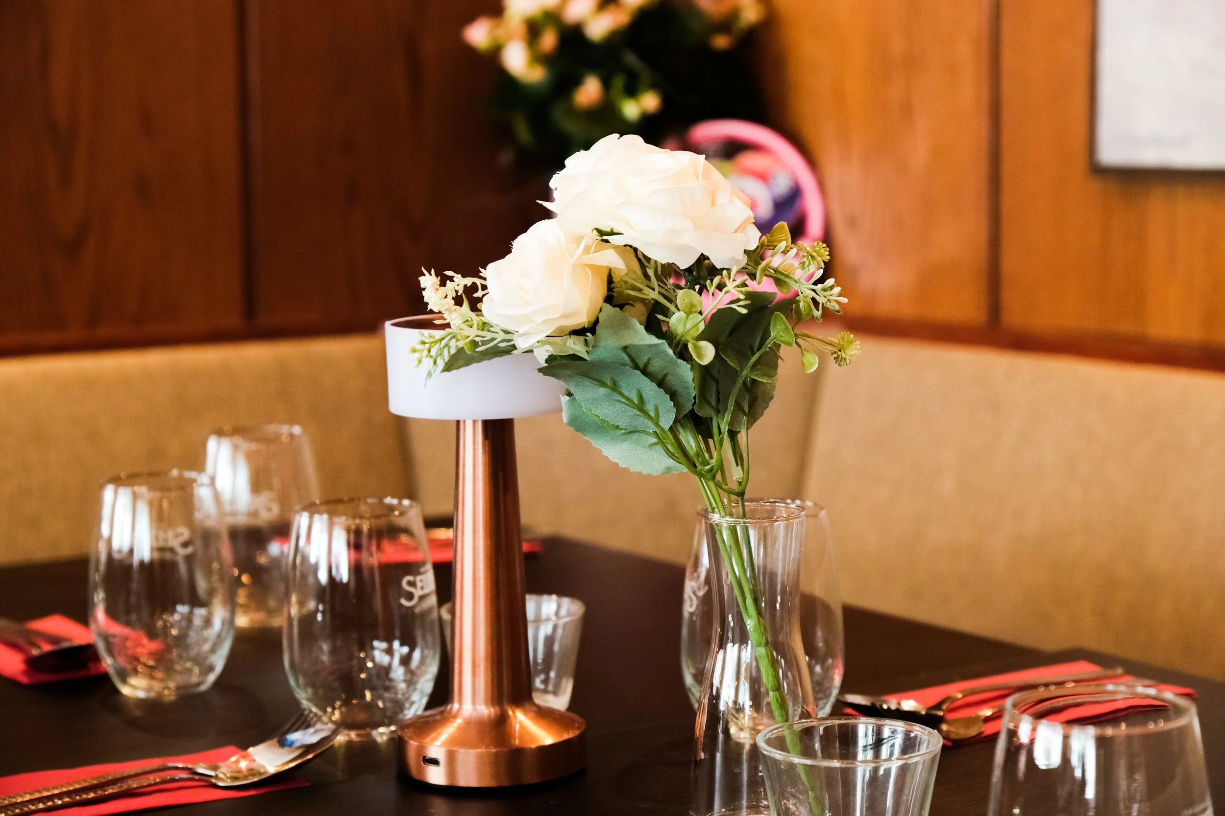 Table setup with a floral centerpiece, glassware, and utensils in a restaurant dining area.
