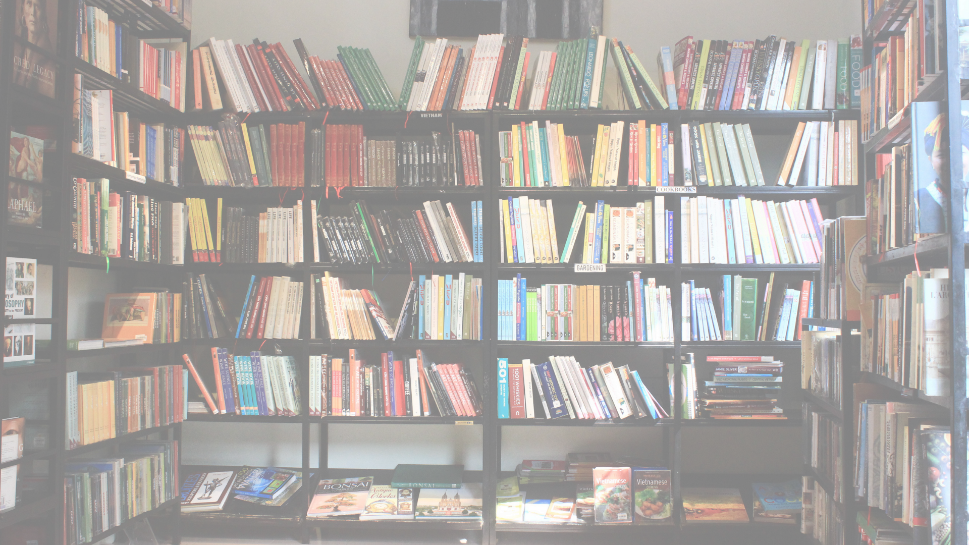 Wall of bookshelves filled with various books, some stacked horizontally, in a bookstore or library.