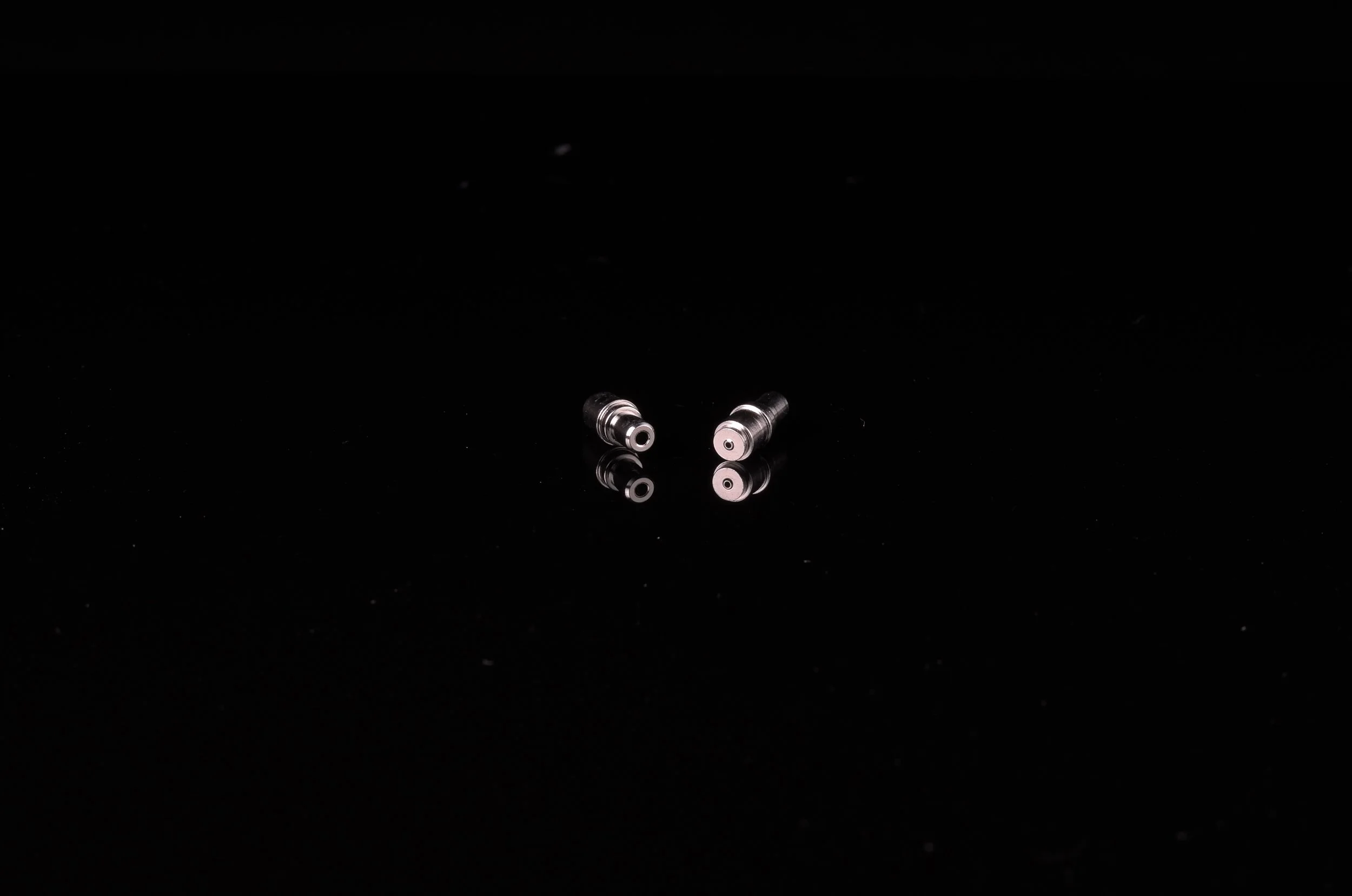 Two small, metallic cylindrical precision product