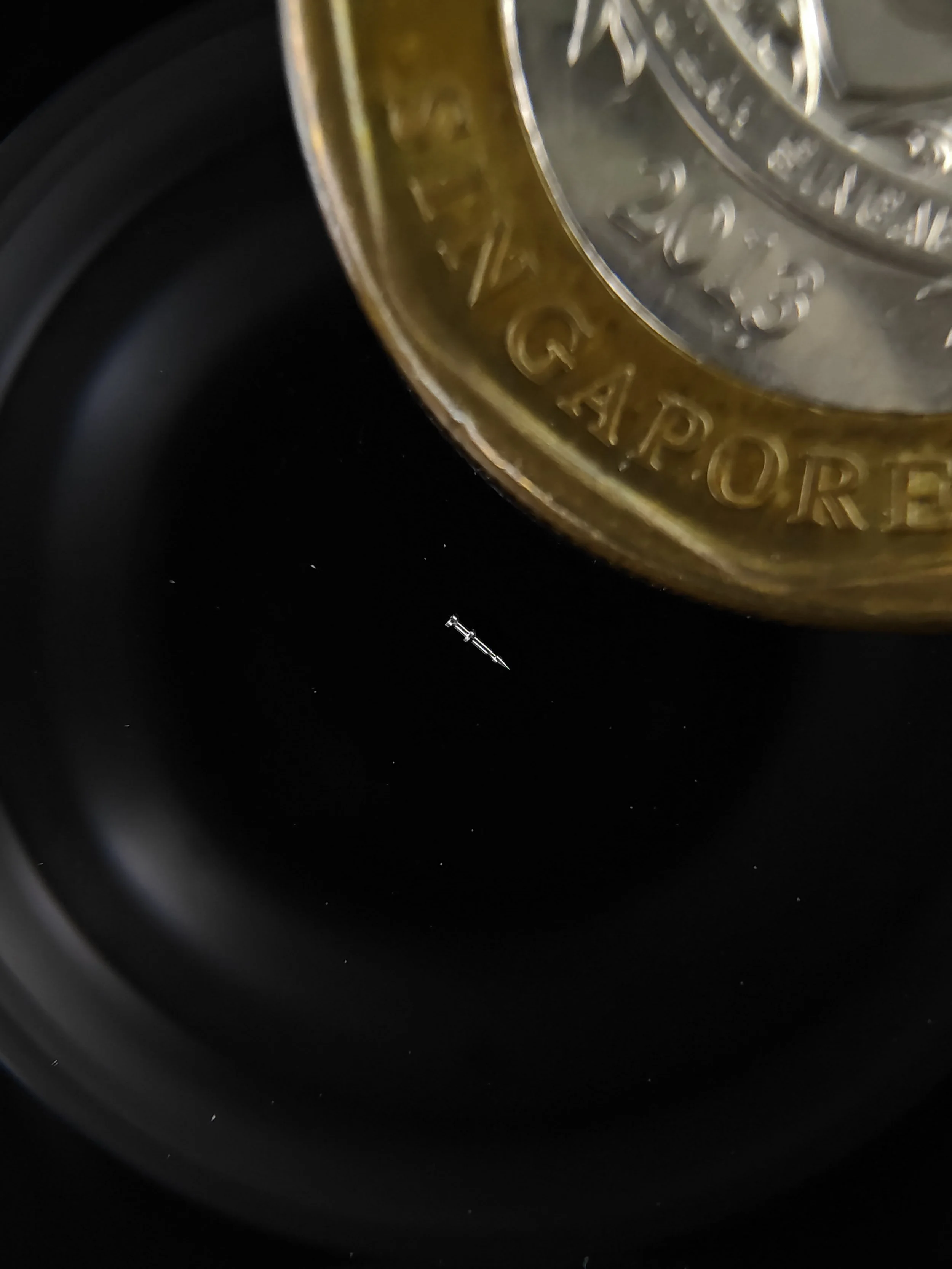 Close-up of a tiny highly precise part with a Singapore dollar