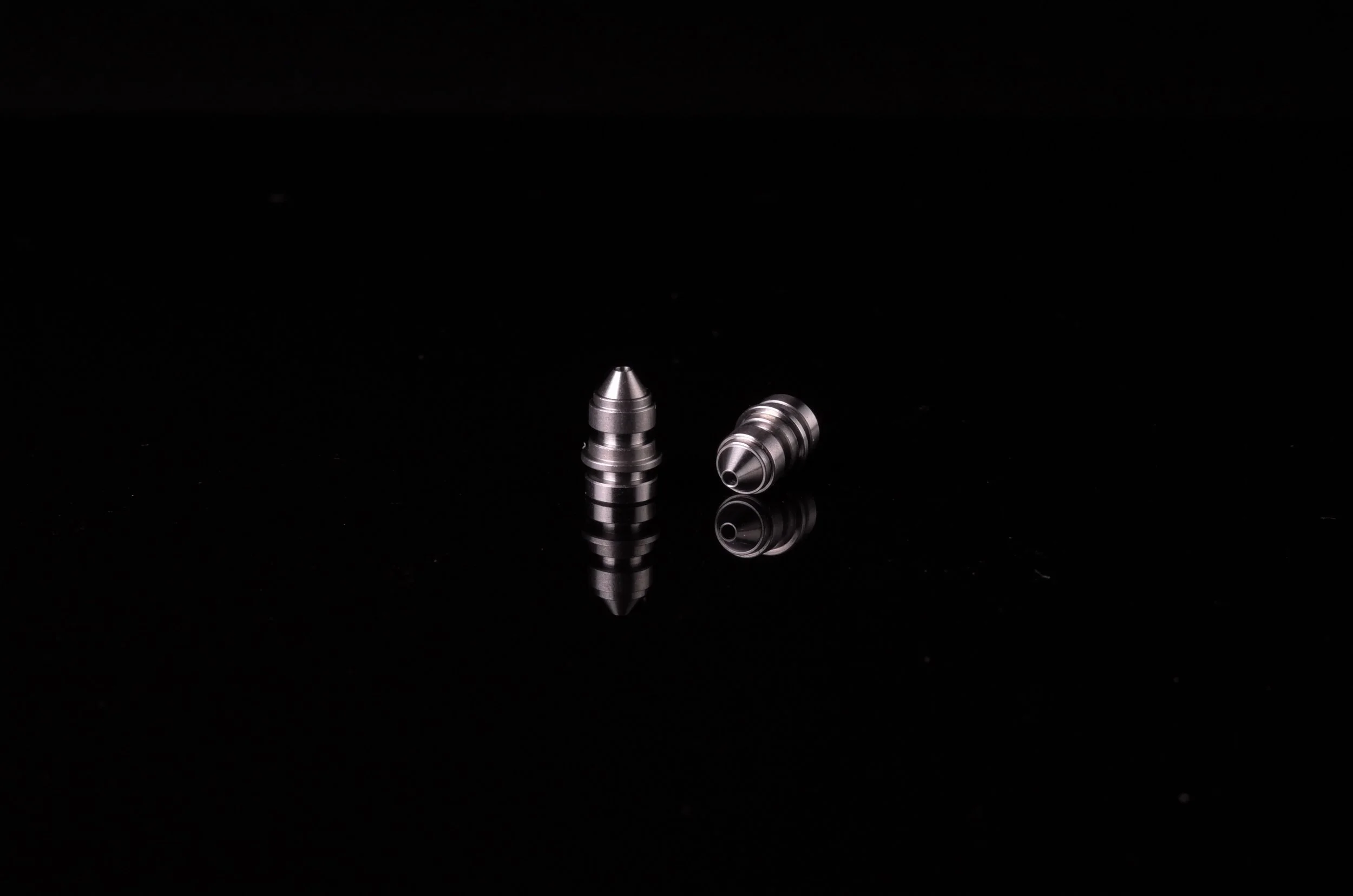 Two small metallic bullet-shaped parts manufactured to tight tolerance