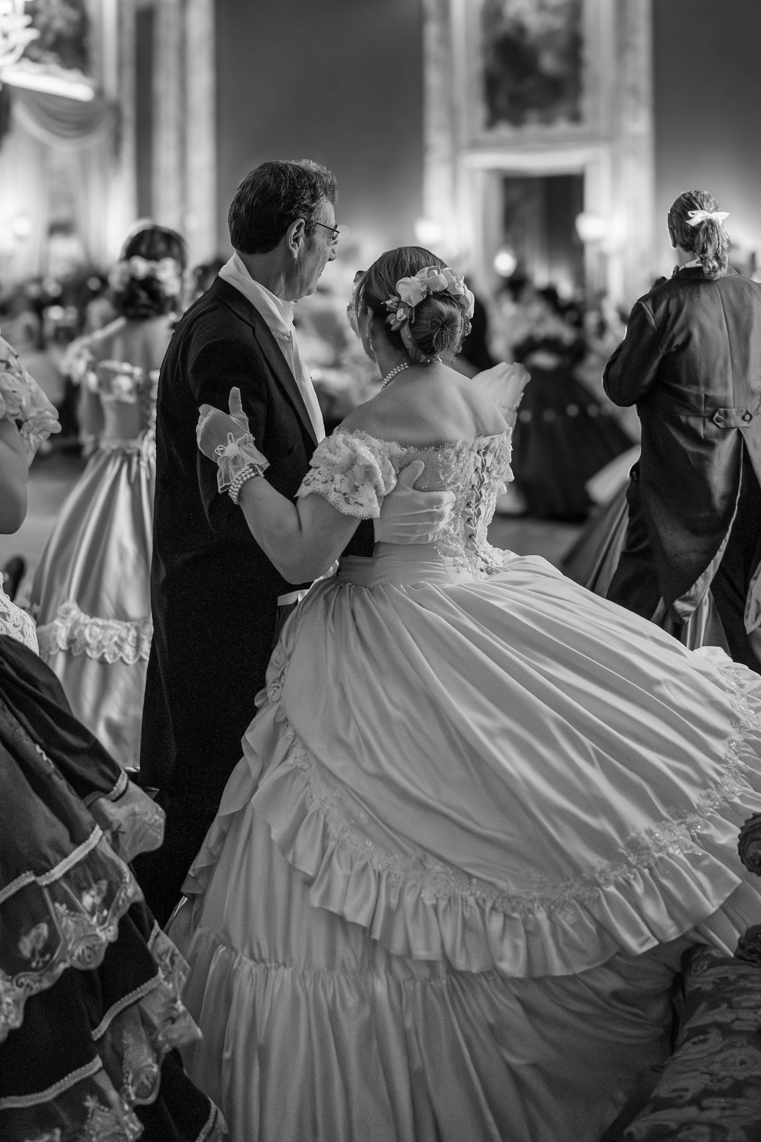 Coppia di sposi in abiti da matrimonio che ballano durante un ricevimento in una sala decorata elegantemente.