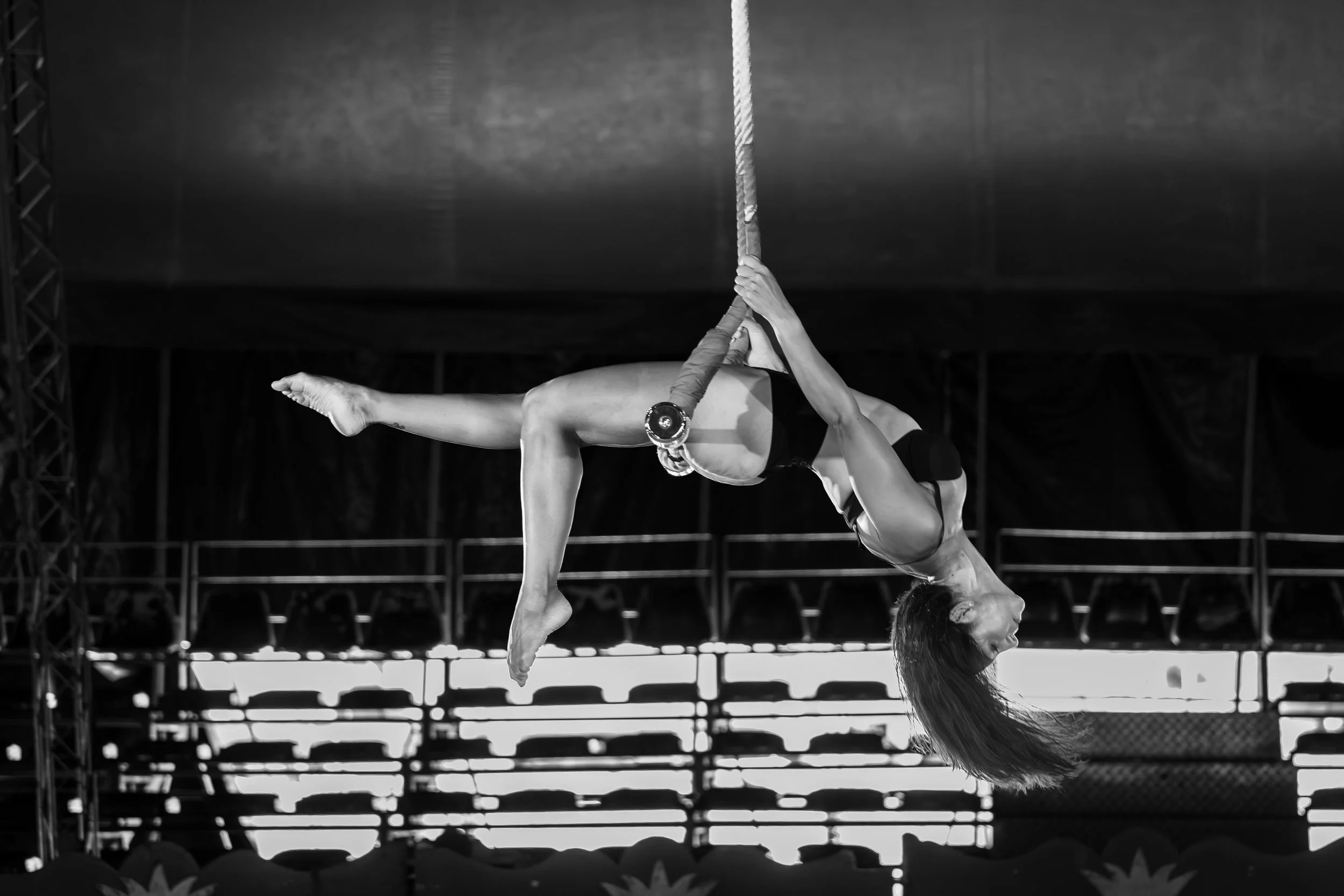 Due ginnaste fanno una coreografia acrobatica con una corda in un ambiente di spettacolo, in bianco e nero.
