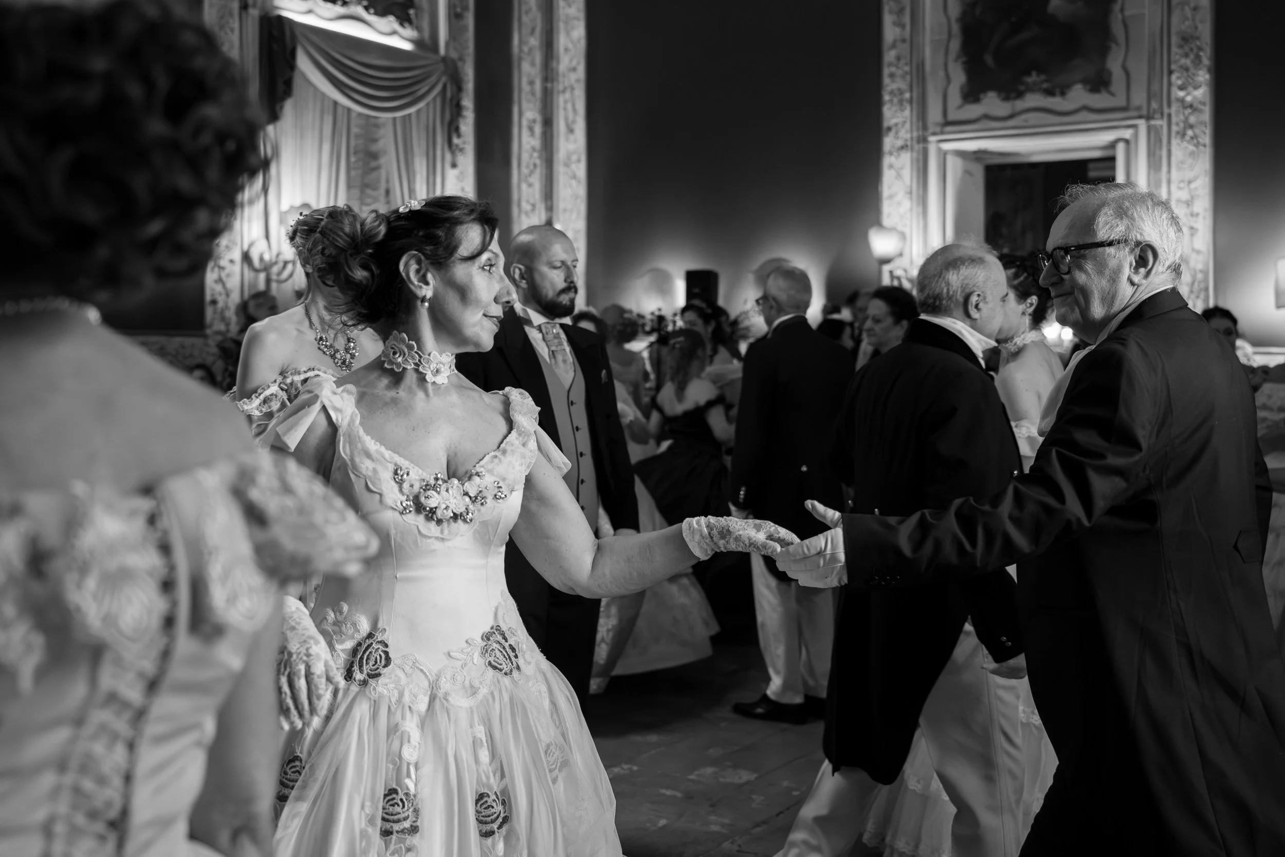 Spose di matrimonio in un ambiente elegante, con una coppia di sposi al centro e invitati intorno, in un salone decorato con aria royale.