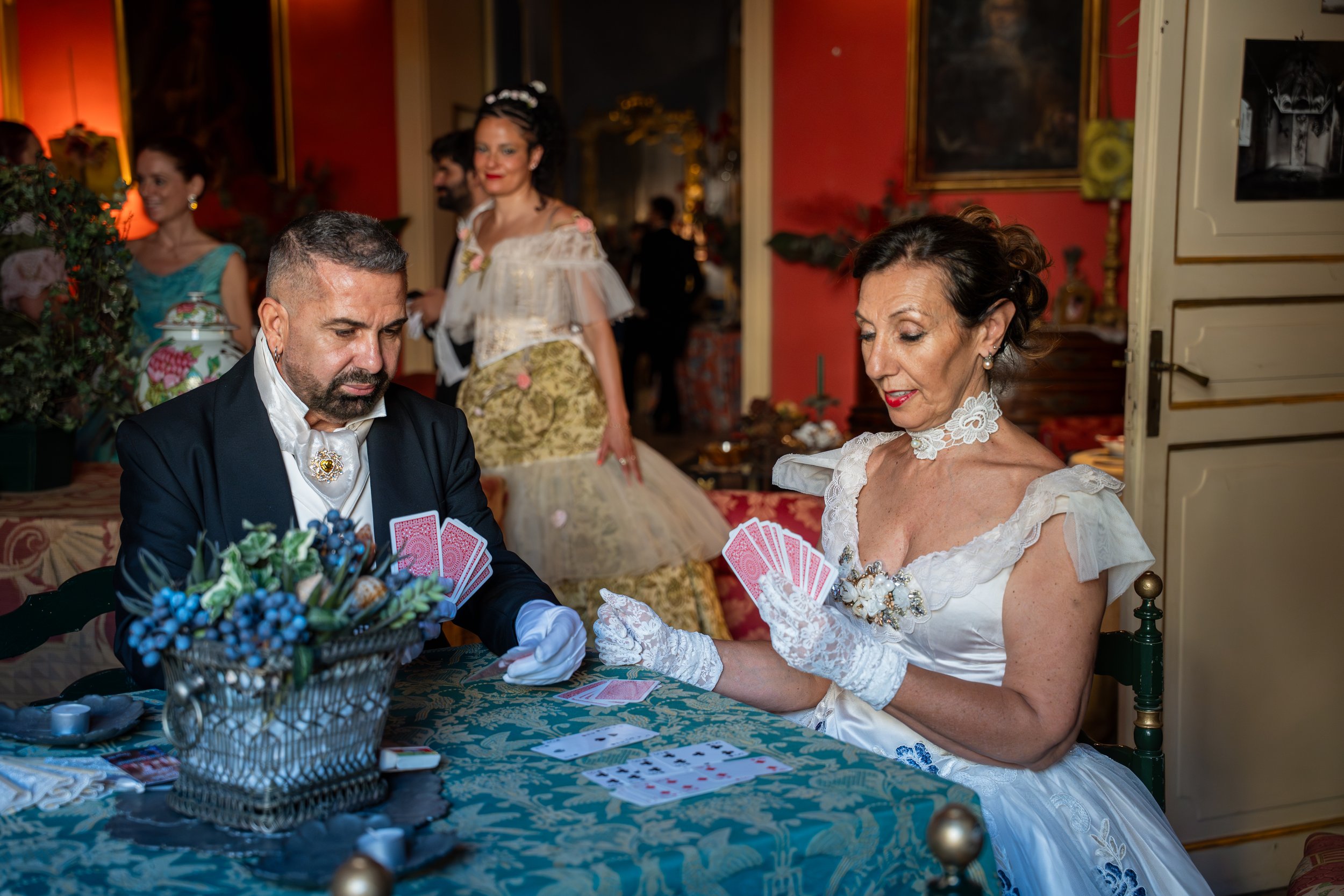 Persone che giocano a carte durante un matrimonio in una stanza decorata elegantemente.