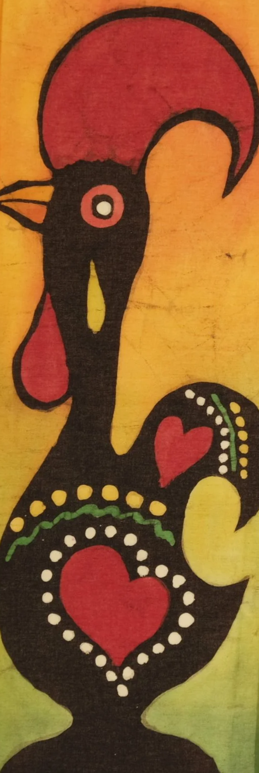 Colorful batik painting of a Portuguese-like rooster with decorative hearts and dots, painted in red, black, yellow, and green, set against a rainbow-colored background.