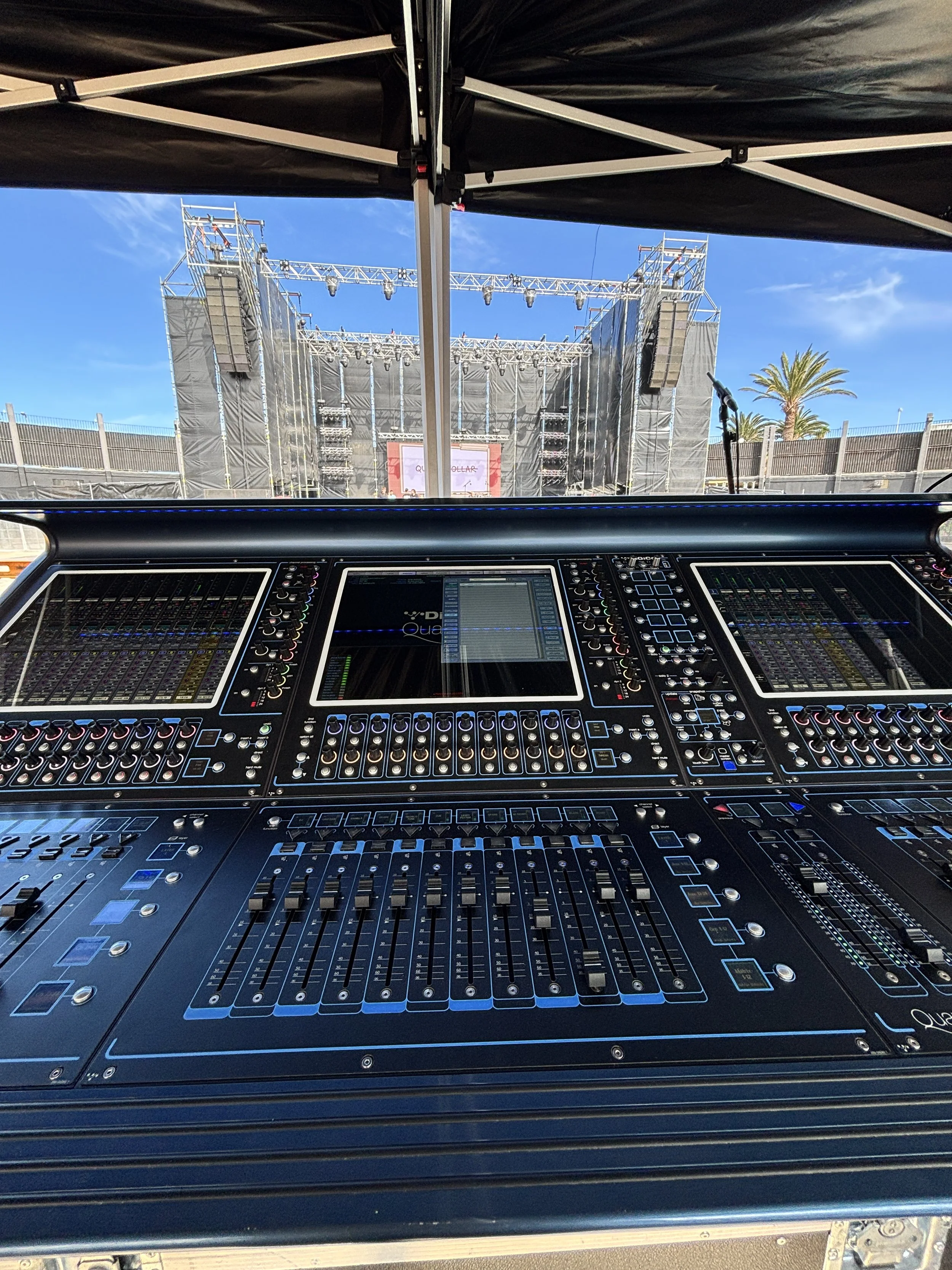 Consola de mezcla FOH preparada para producción de sonido en escenario de festival