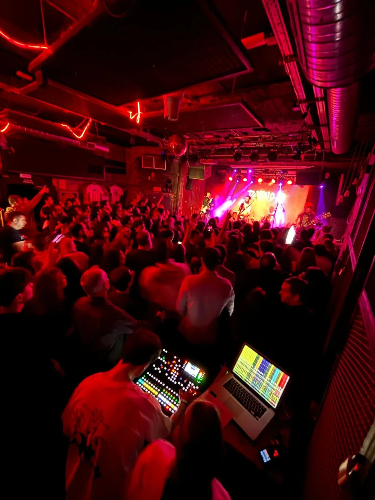 Técnico de sonido operando mezcla FOH durante actuación en directo en sala de conciertos