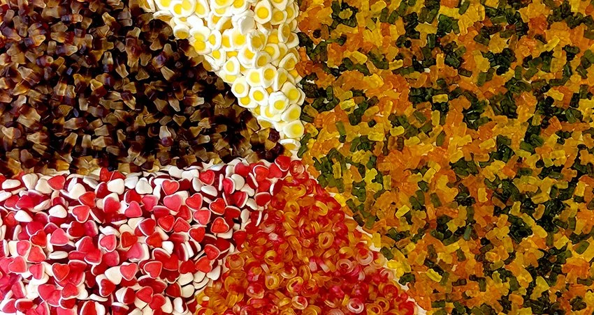 A collection of colorful gummy candies in various shapes and colors, including black, white, red, orange, and yellow, arranged in separate sections.
