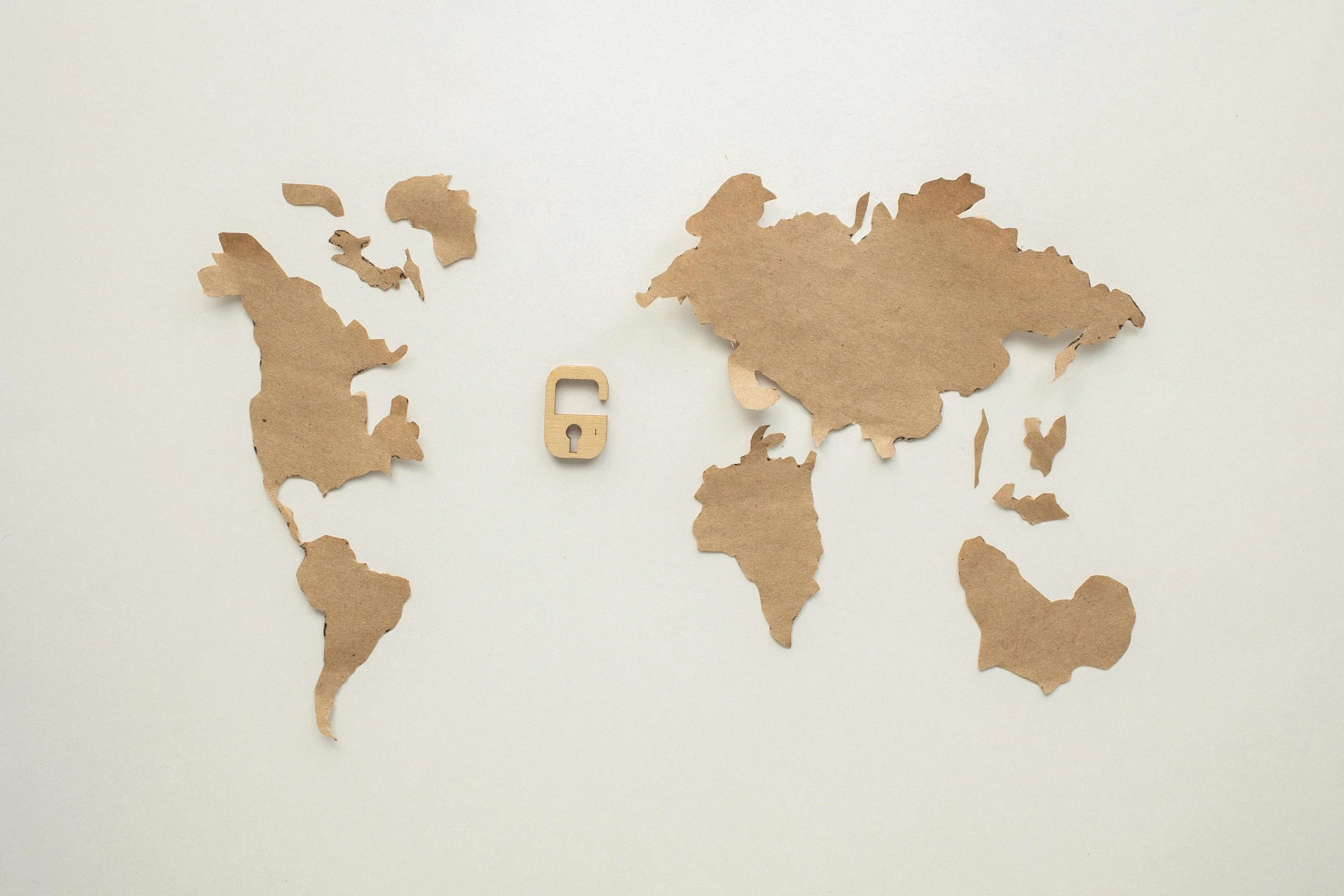 World map made of cardboard cutouts with a small wooden lock symbol in the center.