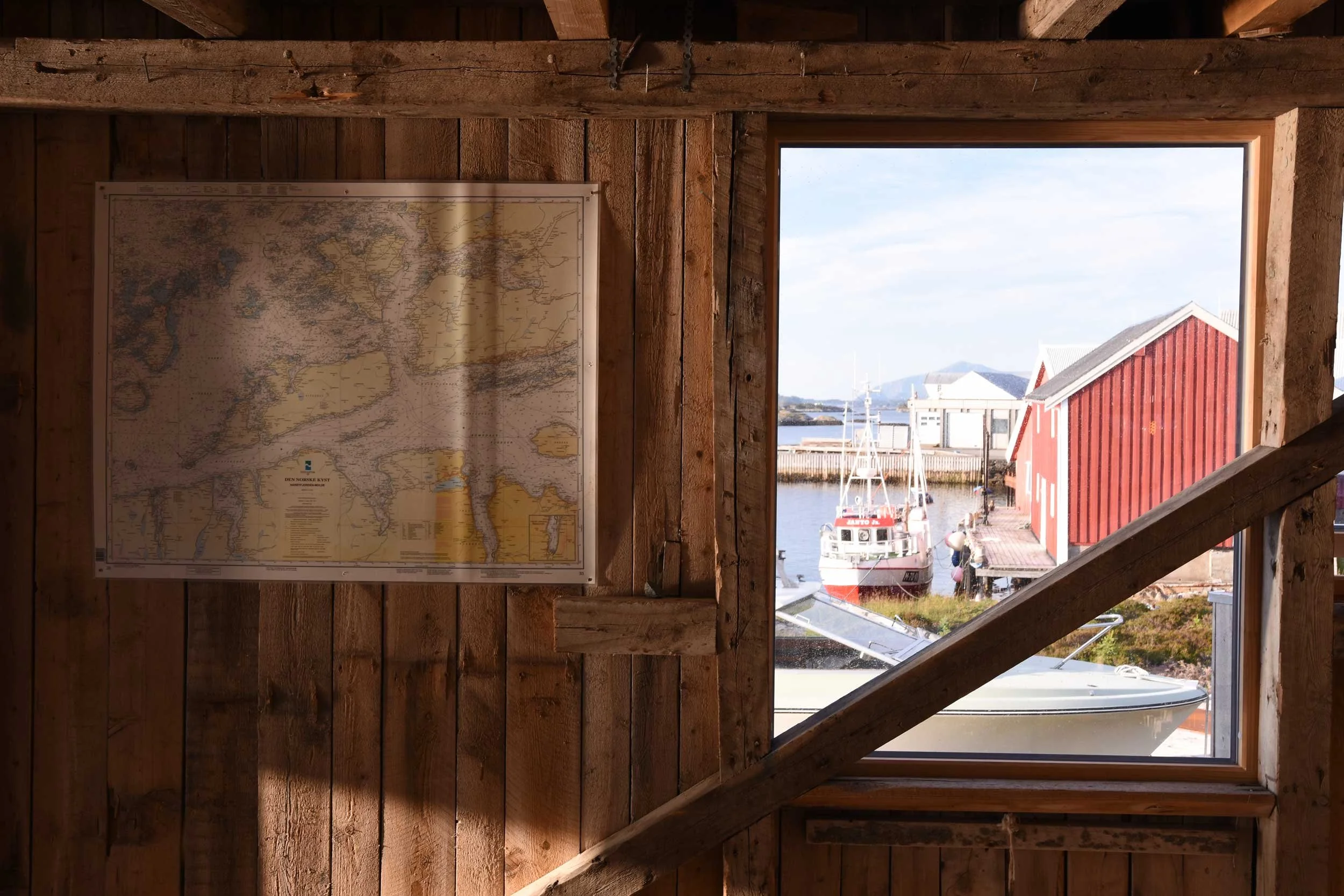 Rustikke vegger på restaurert sjøbu med kart på veggen.