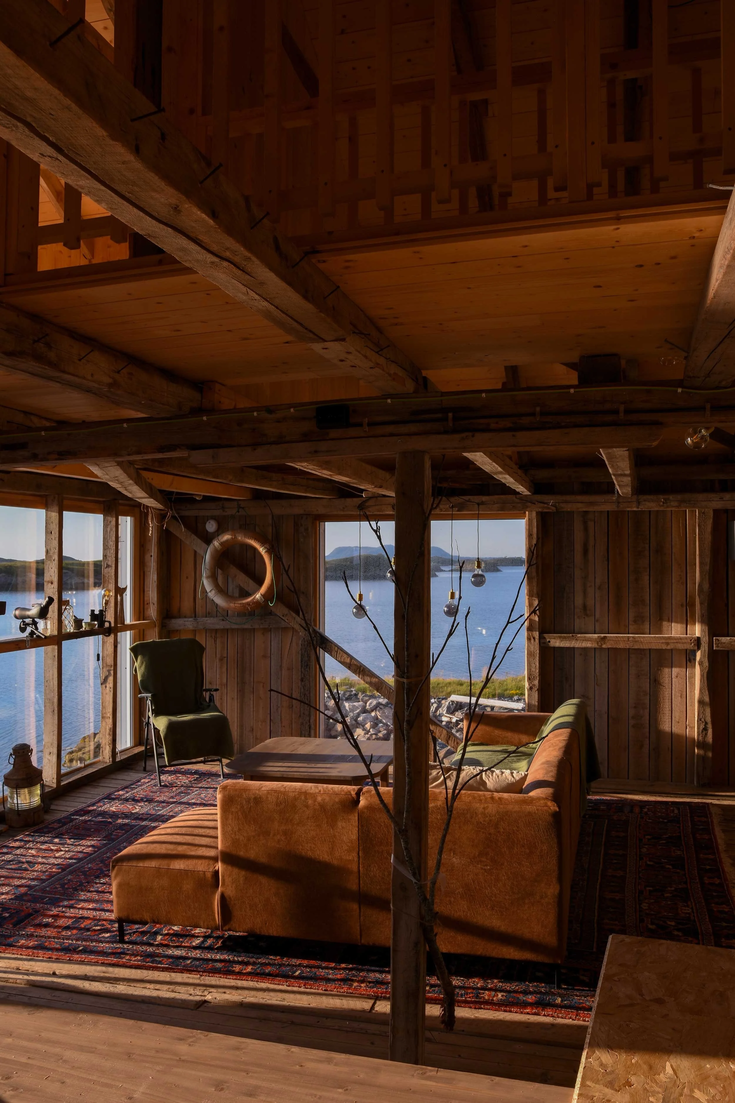 Sofakrok i rustikk feriehus med utsikt over havet og holmer.