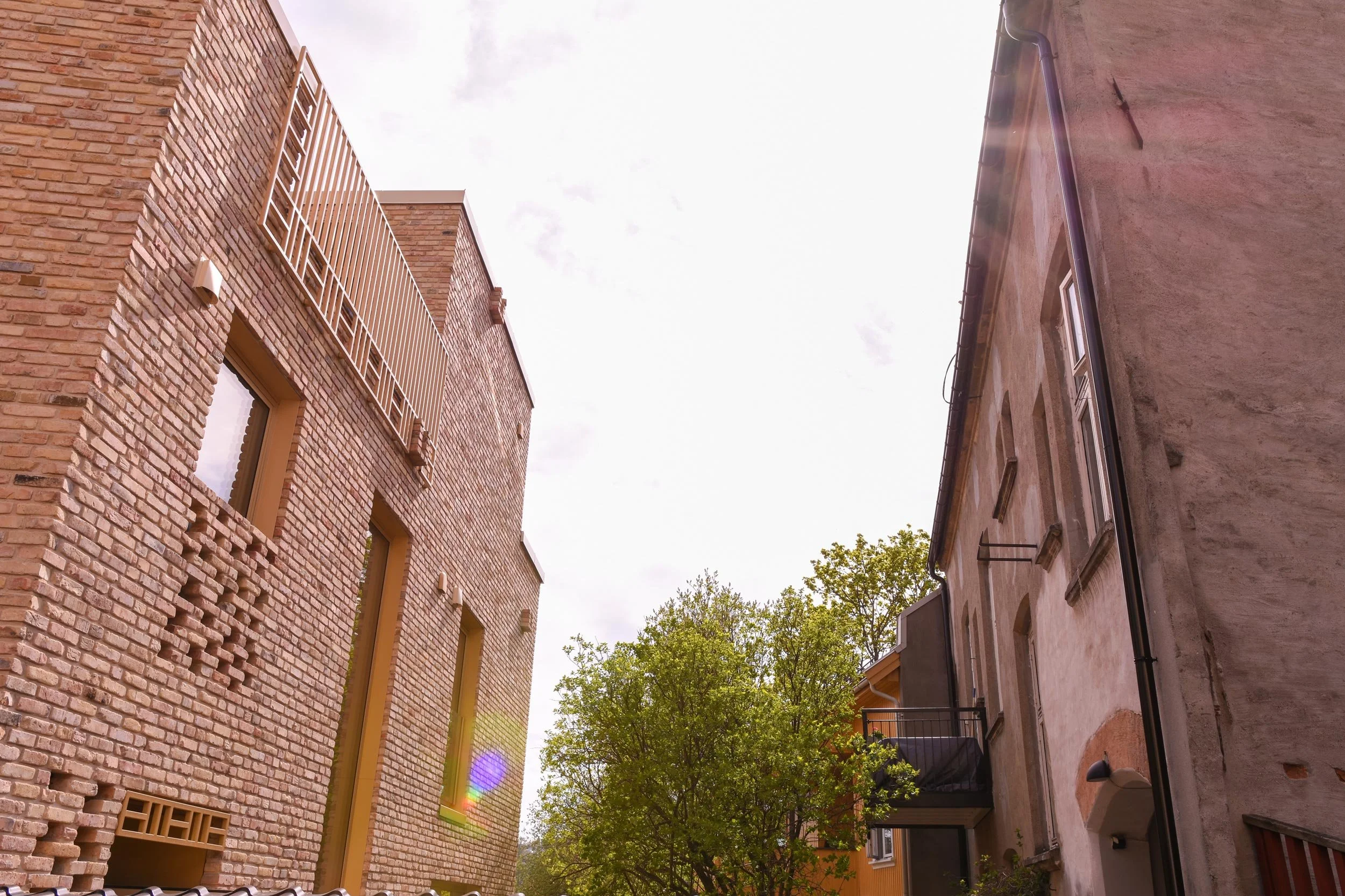 En liten bakgård med et lite tre på Kampen i Oslo med fasaden av tegl til Røverhuset på venstre side.
