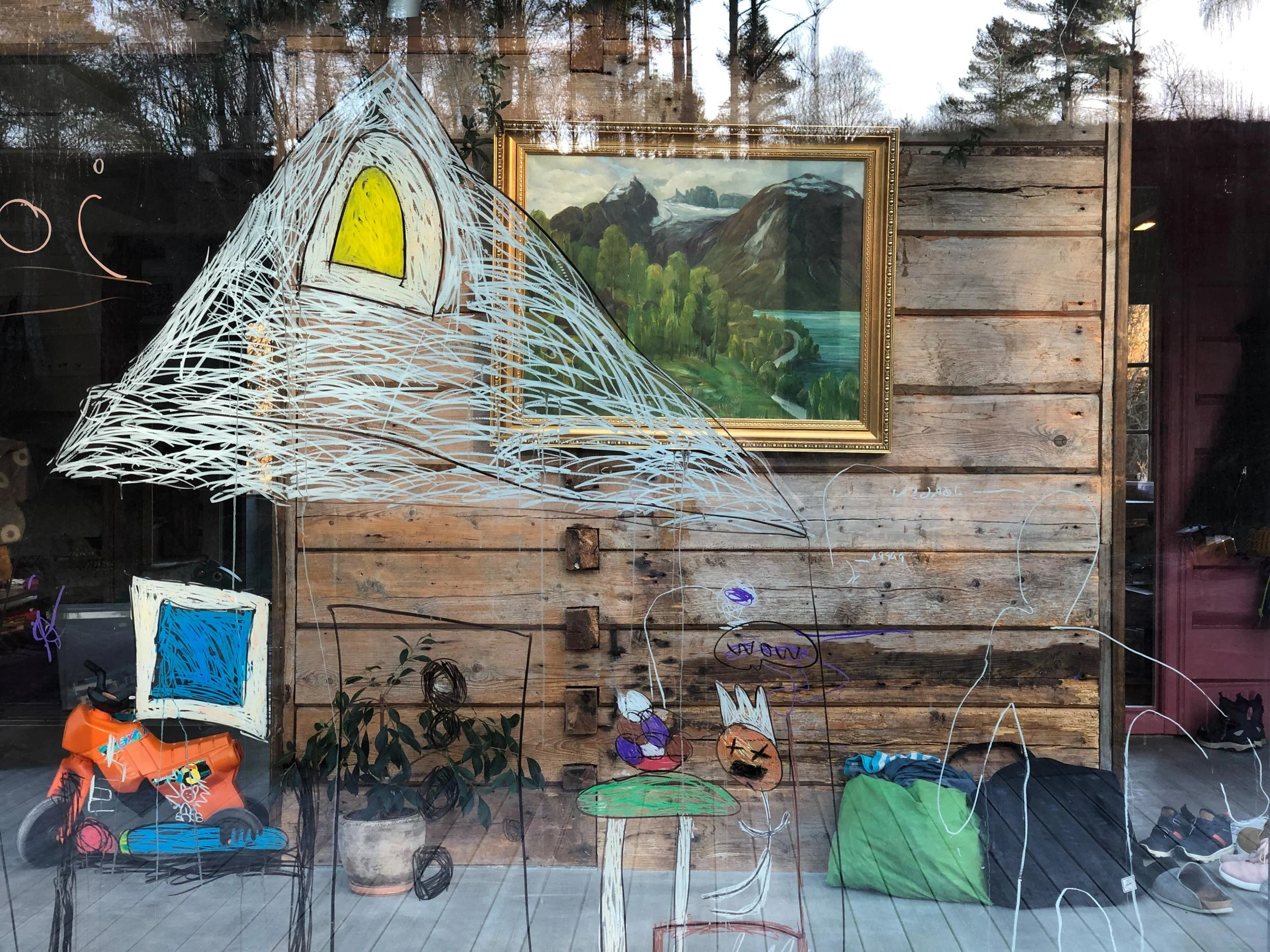 Et stort glassfelt som er tegnet på av barn forran en gammel tømmervegg med klassisk maleri.