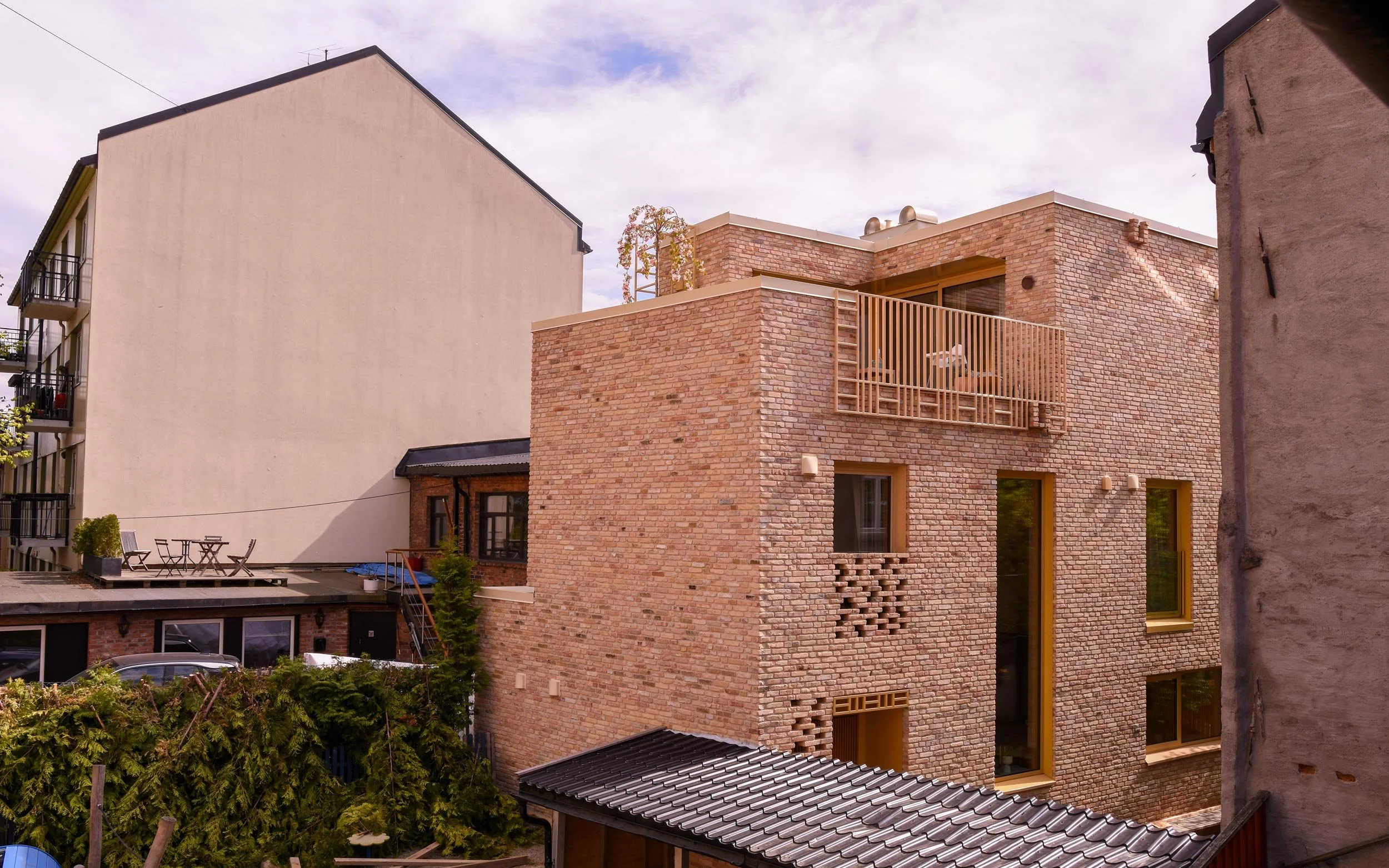 Røverhuset med takterrasse, tegl fasader og gule vinduer vist med bakgården på Kampen i Oslo.