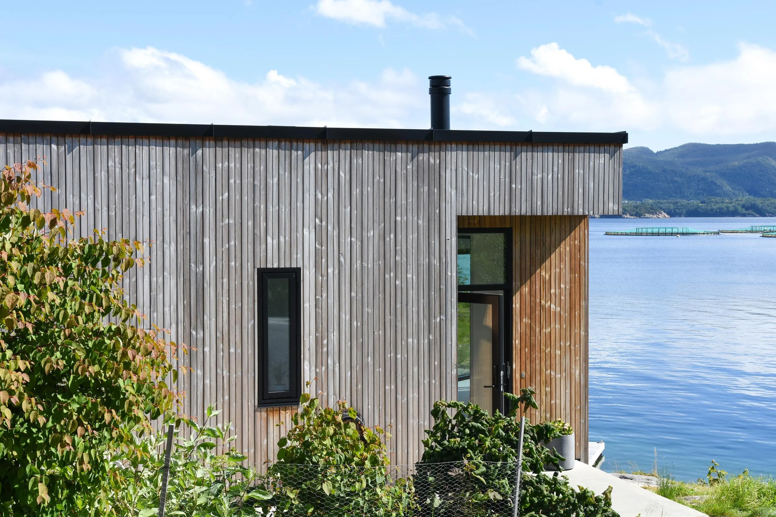 Inngangen sett utenfra med hage og utsikt til havet rett bak.