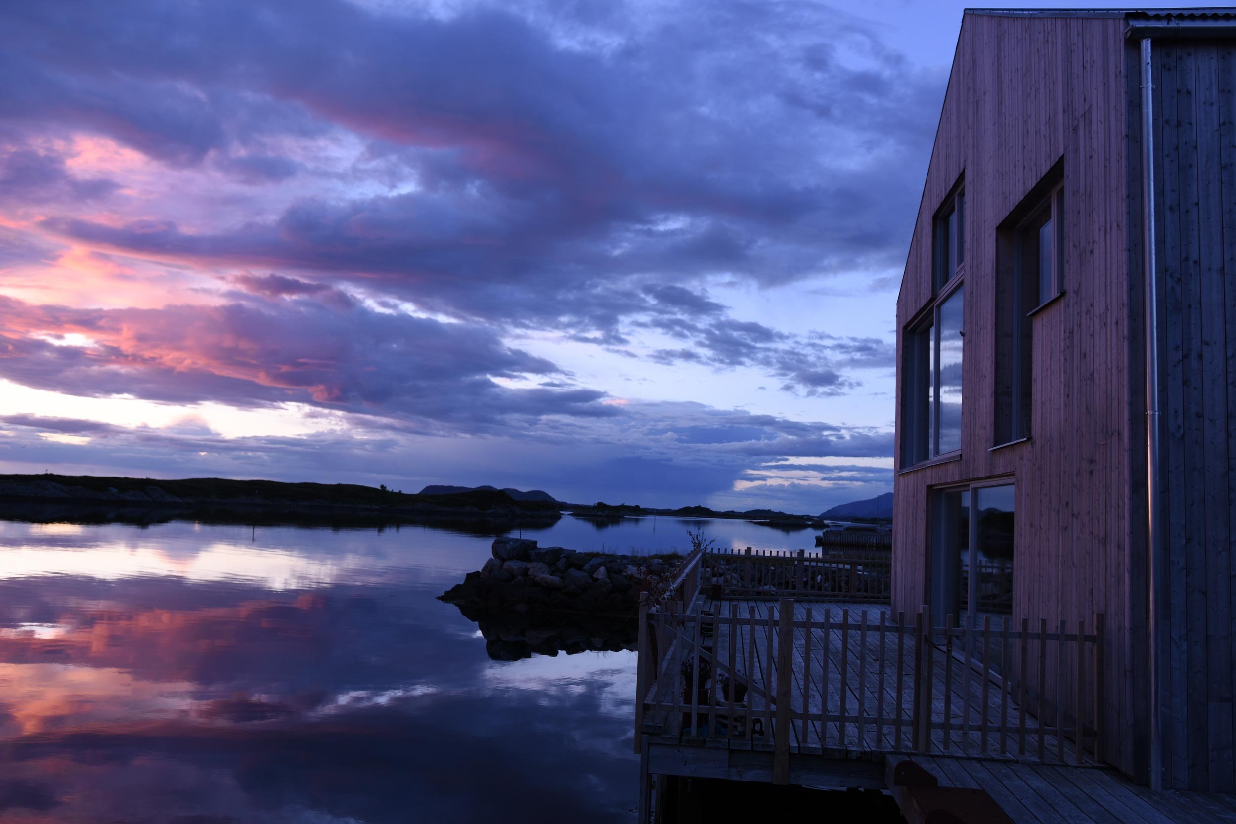 Ny fasade med tetris vinduer ut mot solnedgangen over sjøen.