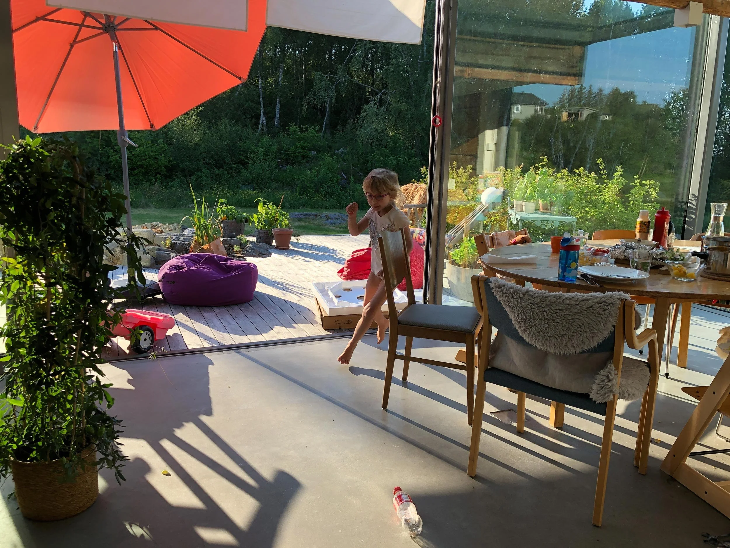 Sommer i Gamlehuset med åpent glassdør skyvefelt som kobler ute terrassen sammen med spisestuen inne. Lek og moro.