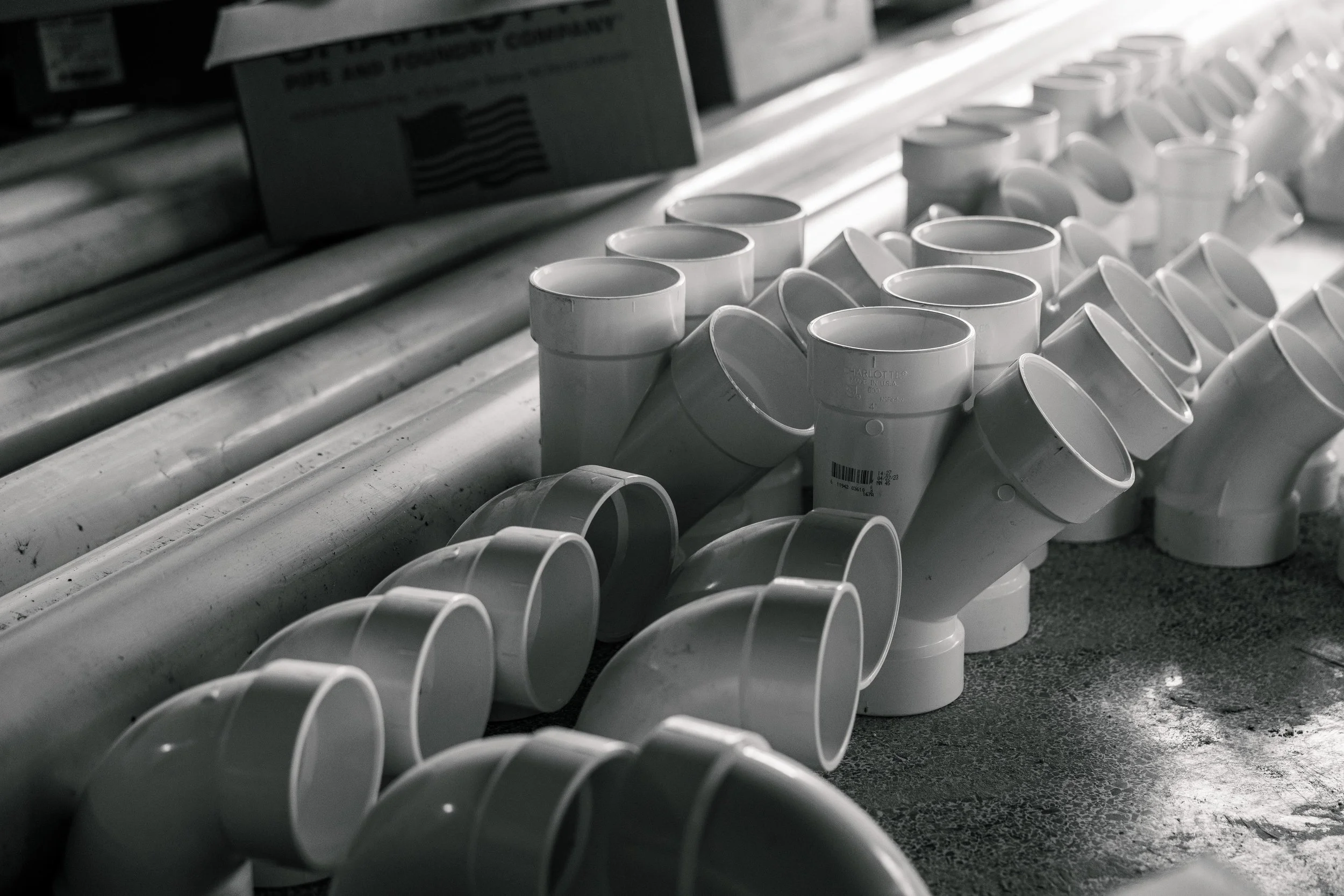 Collection of white PVC pipes and fittings on the floor in a hardware or plumbing store.