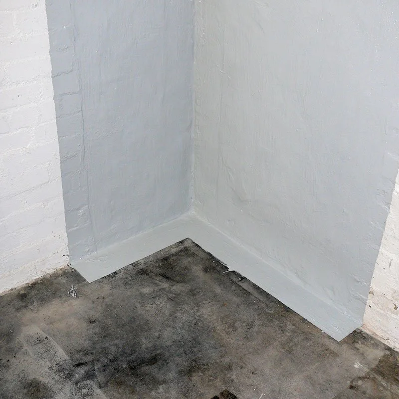 Ecke eines Raums mit weißen gestrichenen Wänden, helle Wandfarbe und dunkler Boden