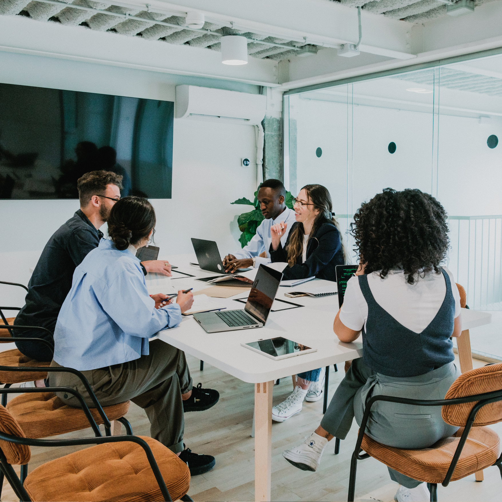A diverse group of professionals collaborating around a conference table, reviewing documents and discussing compliance strategies in a modern office setting.