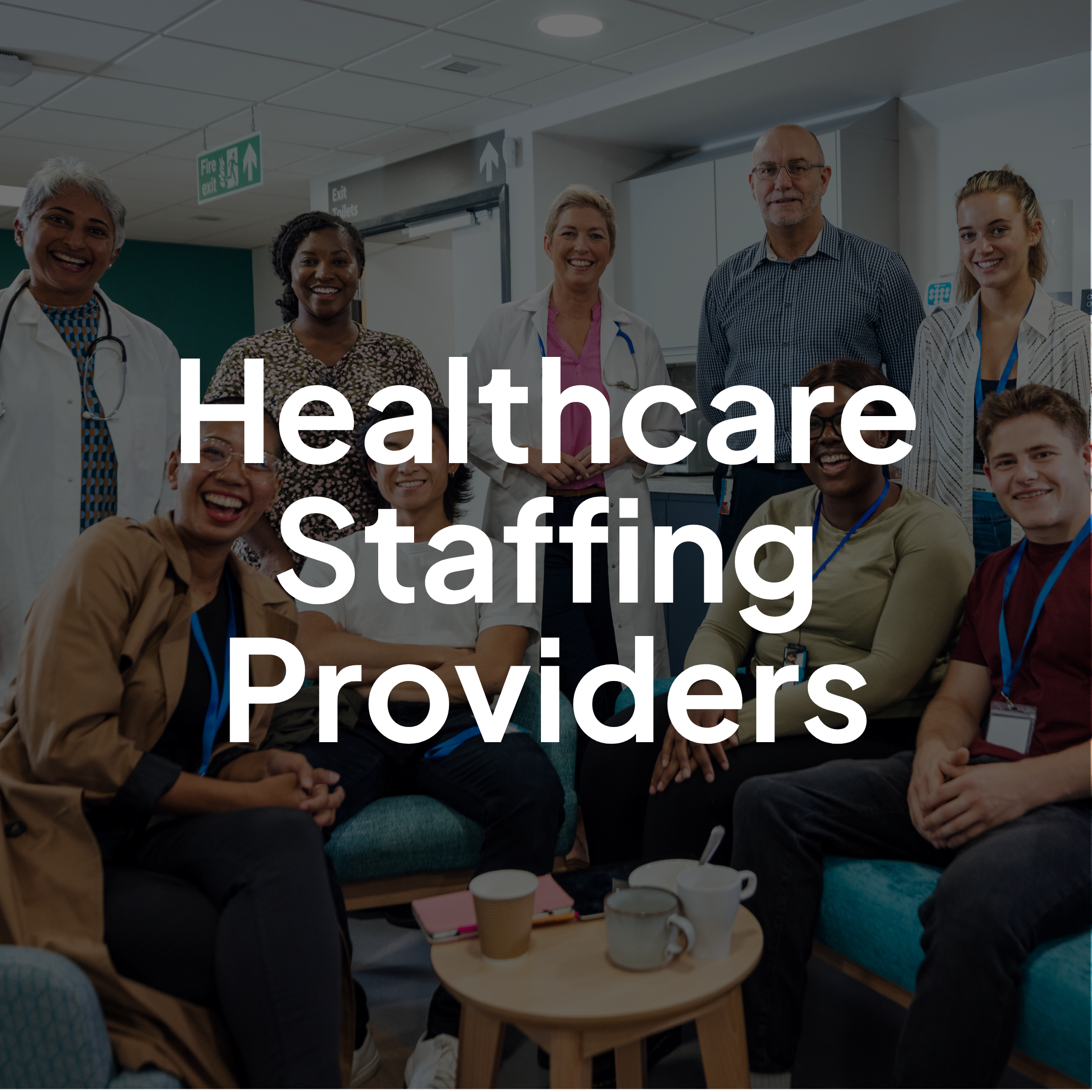 Healthcare staffing providers gathered as a diverse team in a clinical workspace, smiling and collaborating.